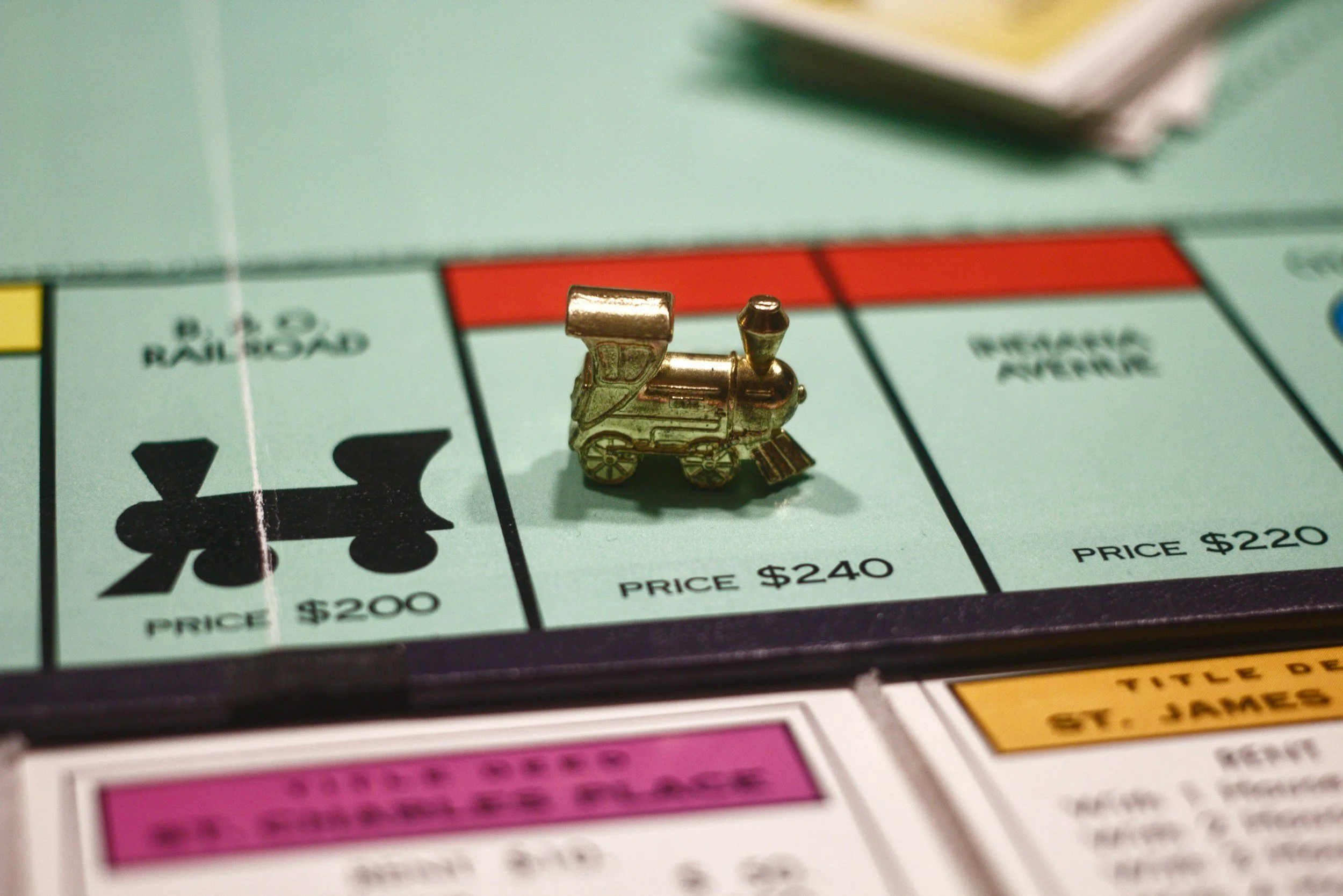A small metallic train token on a Monopoly game board, positioned between properties labeled 'B. 2. 2. Railroad' and 'Tennessee Avenue,' with prices of $200 and $220.