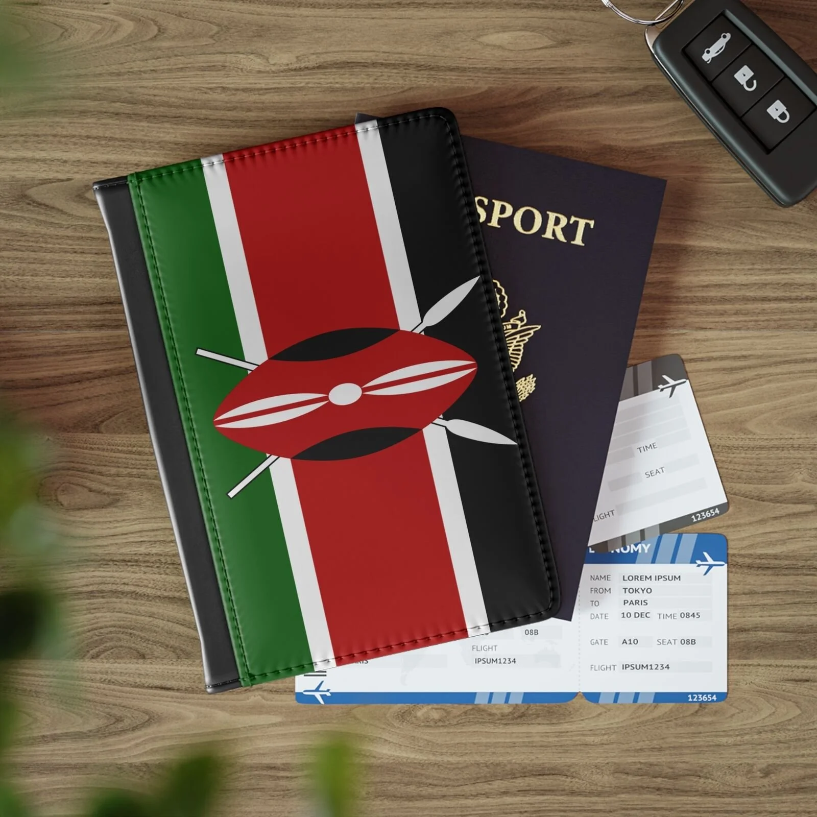 Kenyan flag themed travel document holder on a wooden surface, with a navy blue passport, two airline boarding passes, and a car key fob nearby.