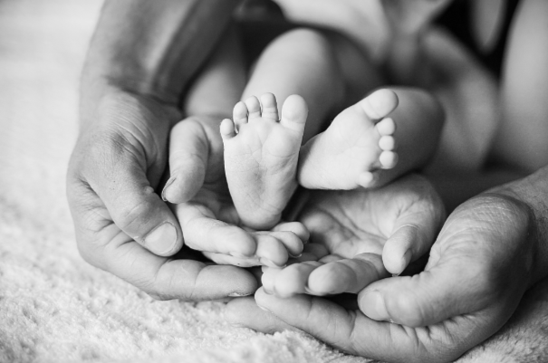 Close-up of adult hands gently holding tiny baby feet.