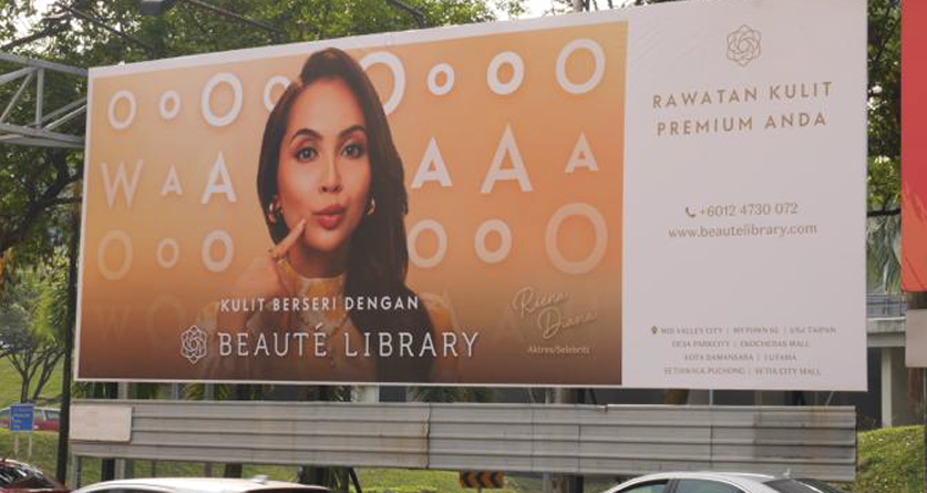 Billboard advertisement for Beaute Library featuring a woman with dark hair applying serum to her face, with a beige background and white geometric circles, promoting skincare for glowing skin.