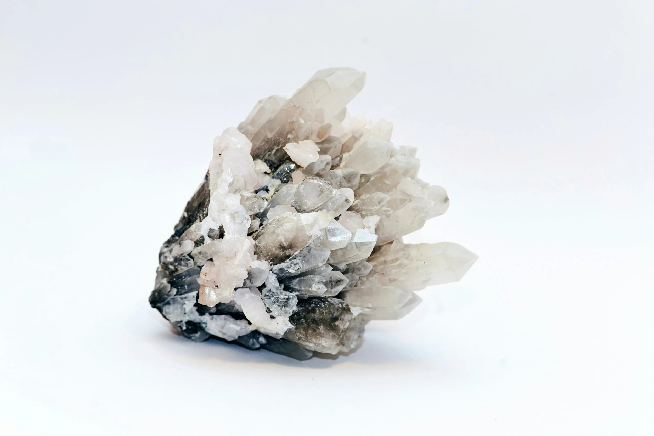 A cluster of clear and black quartz crystals on a white background.