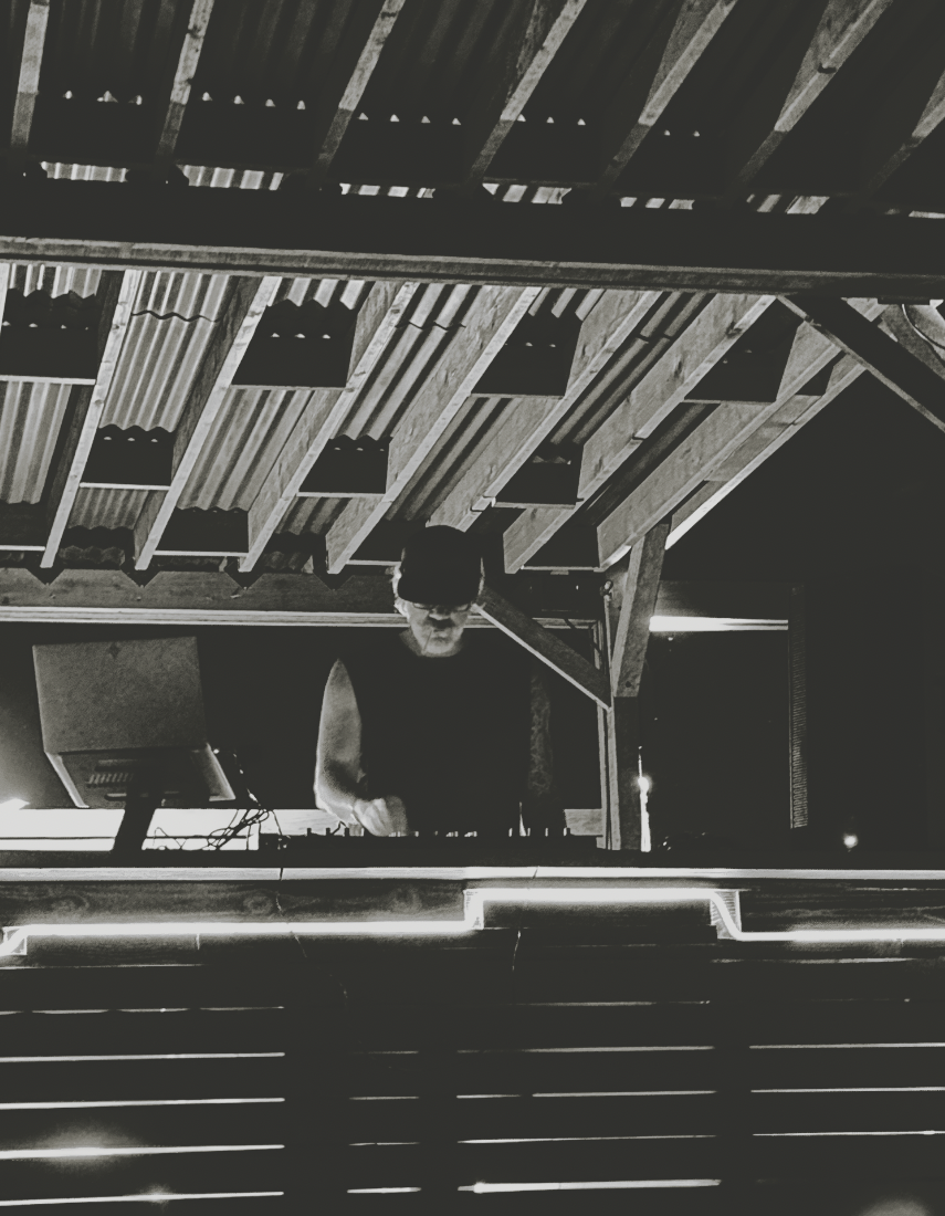 A DJ playing a set in the desert of Joshua Tree under glowing lights and stars.