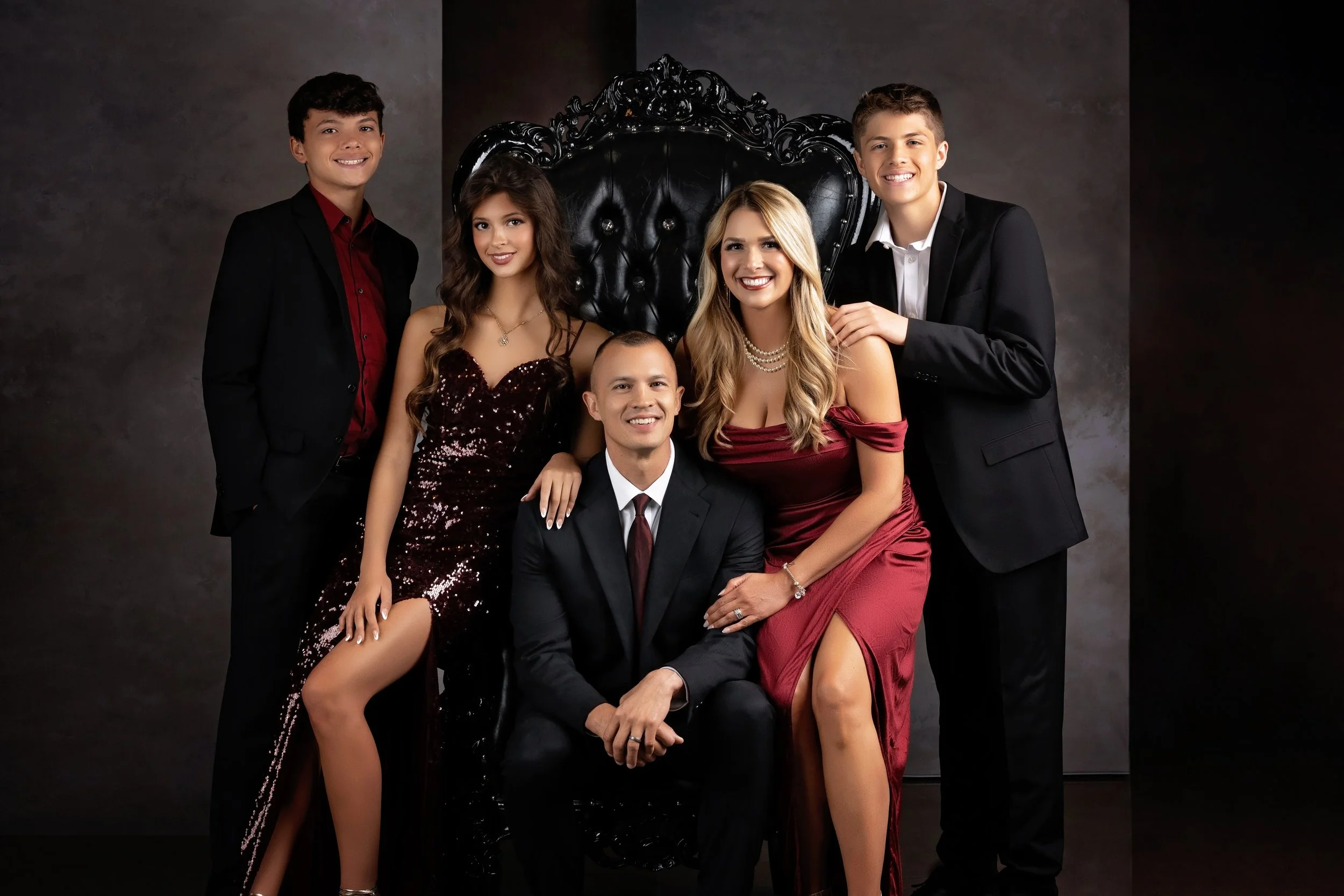 a stunning family poses in studio with a large queens chair in Gretna, Nebraska