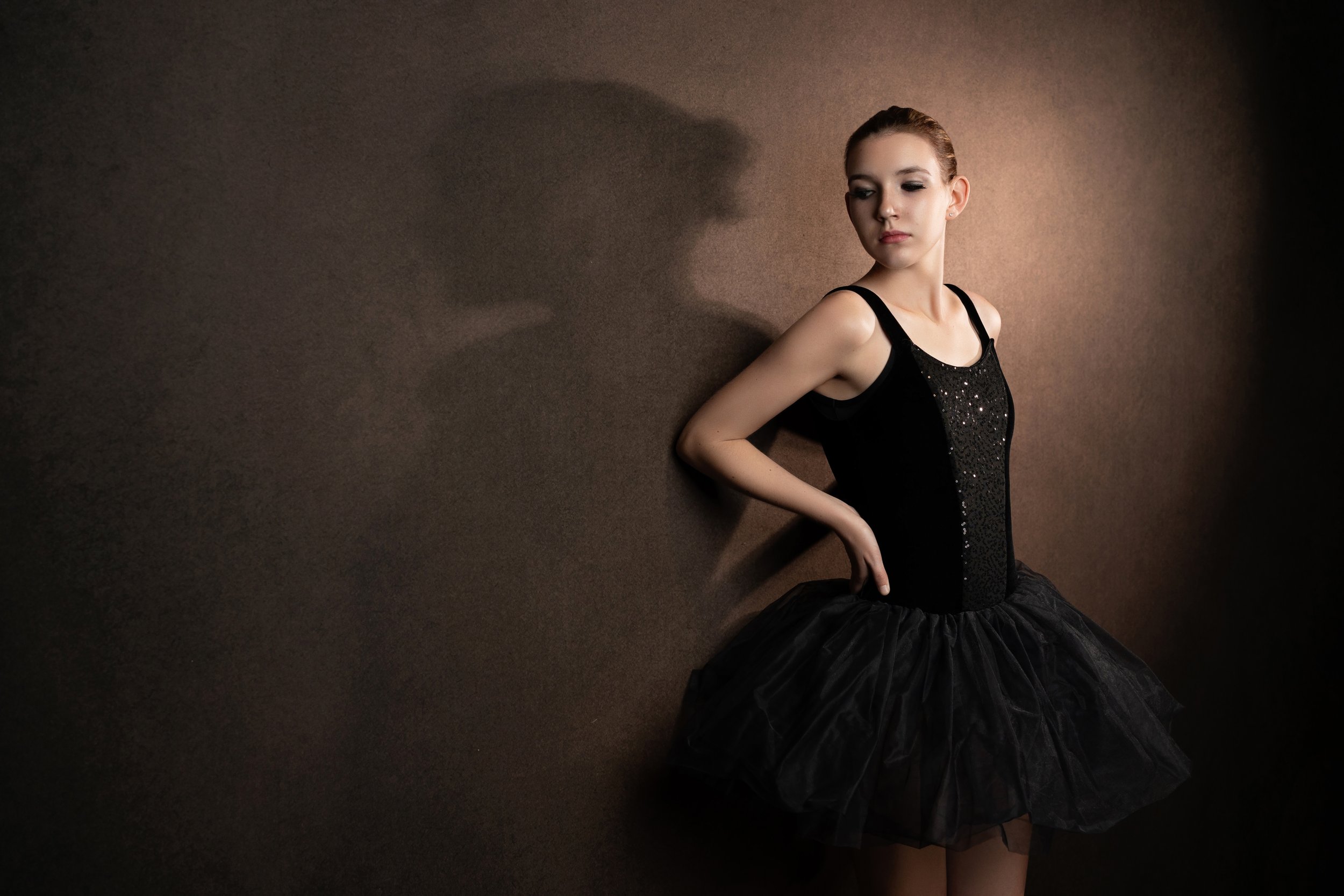 A ballerina poses against a wall with a shadow in Gretna, Nebraska