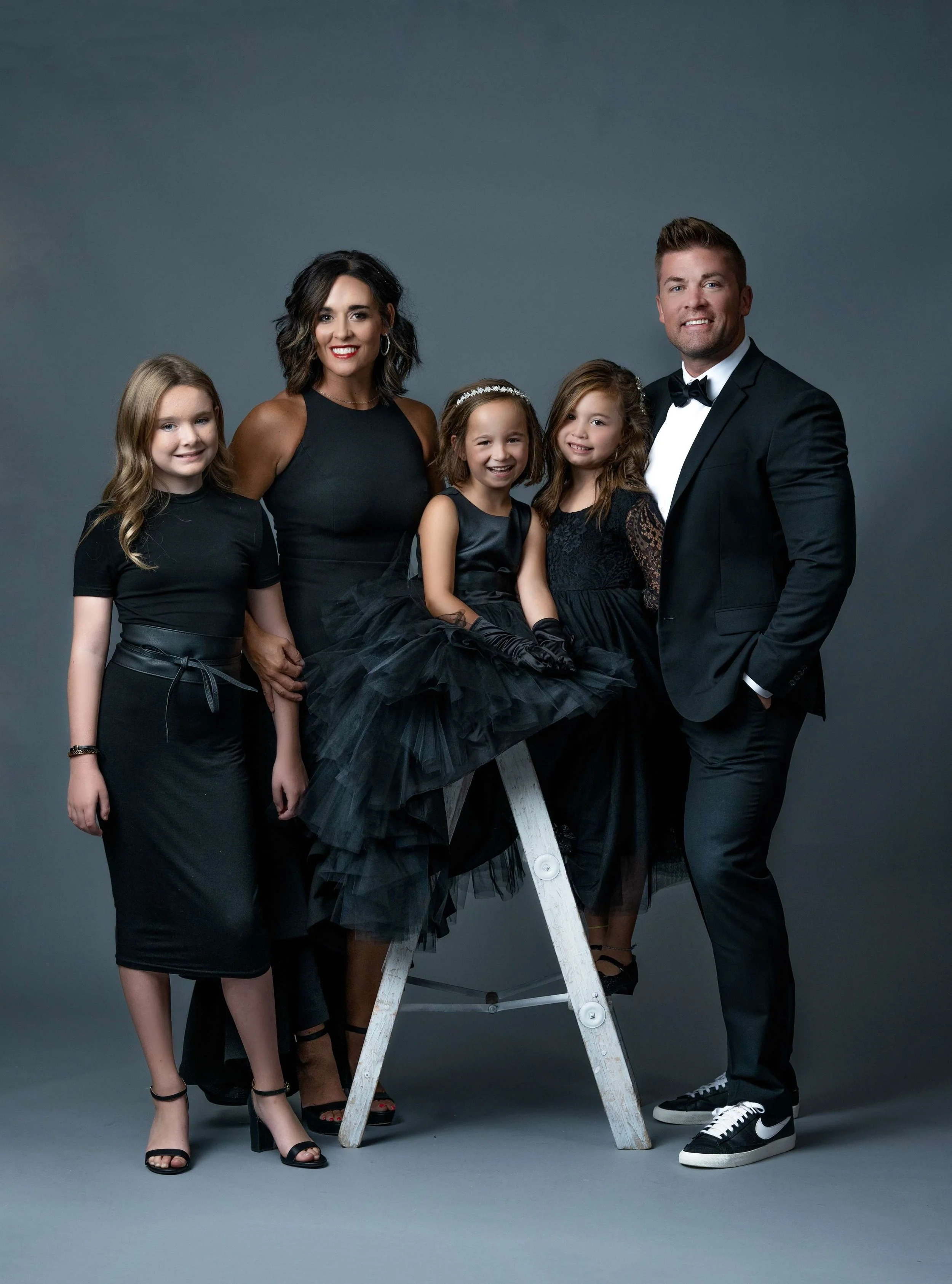 A family of five smiling and laughing together in their studio photo session