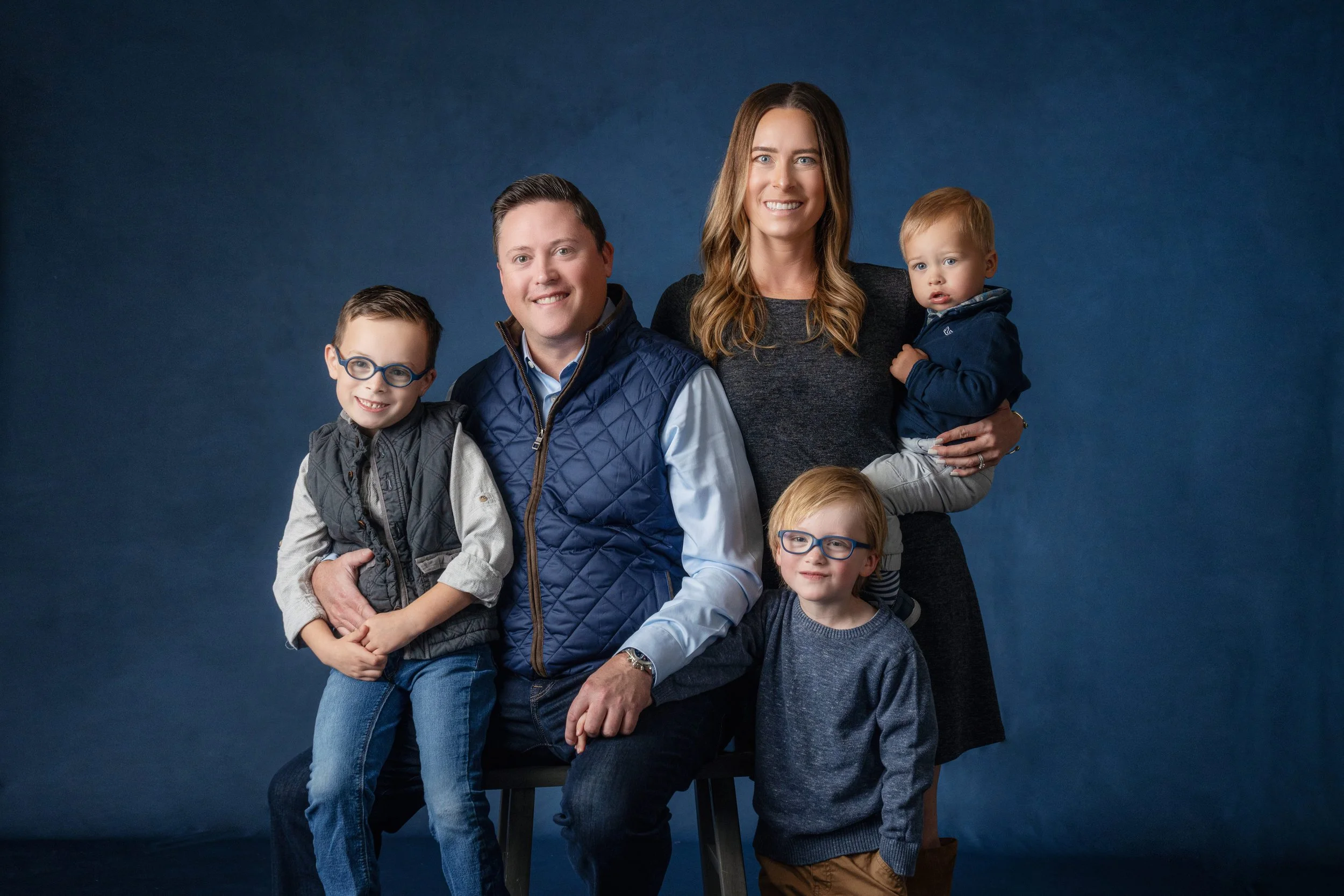 Omaha Nebraska Family portrait with four children and two adults against a blue background.