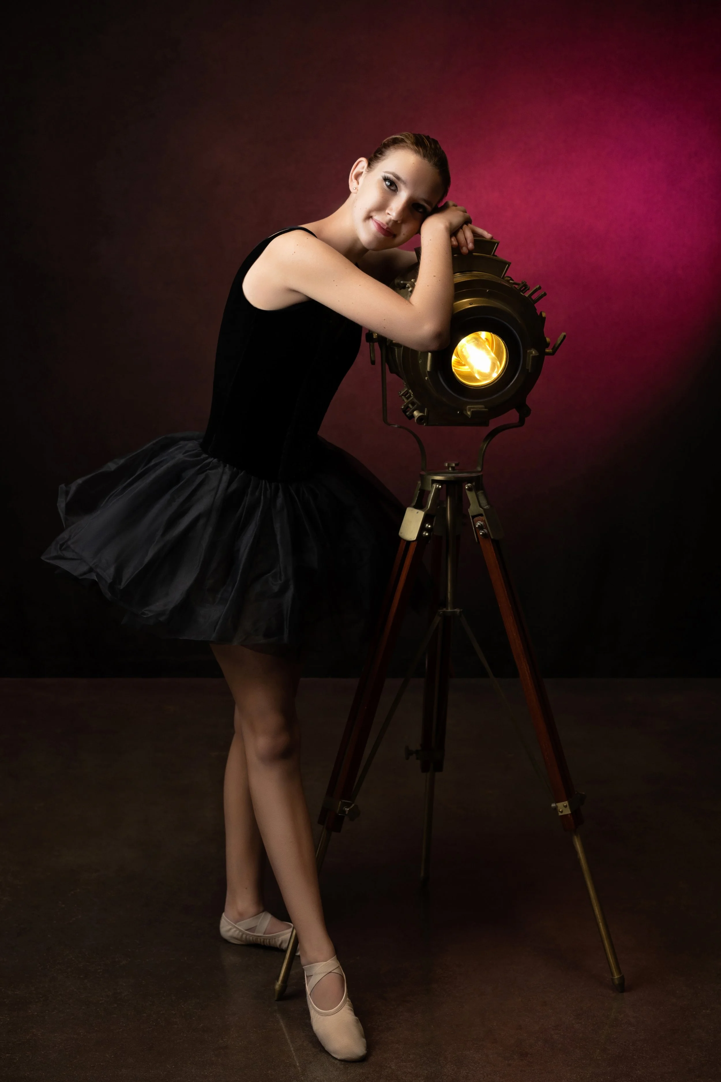 A girl poses with a hollywood light in her black tutu during her dance session 