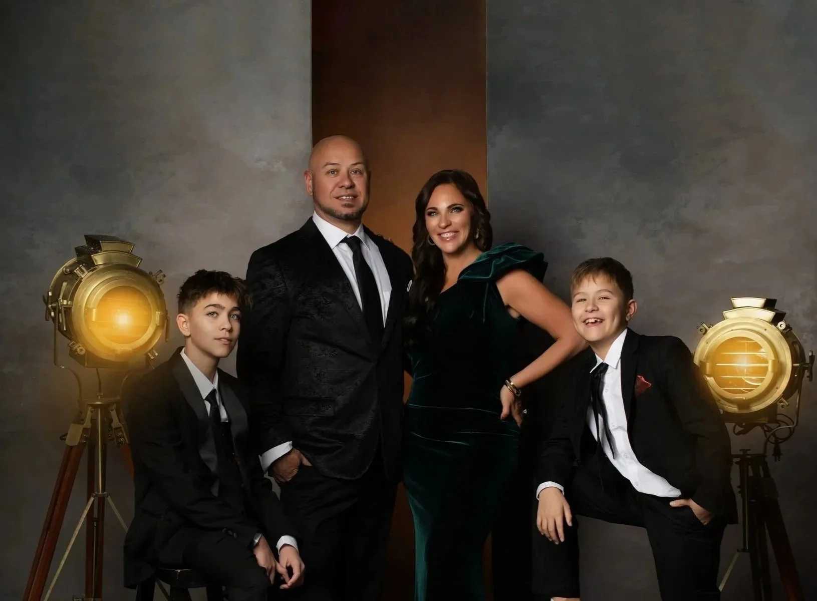 A family of five dressed in formal attire posing together in a photography studio with vintage-style studio lights.