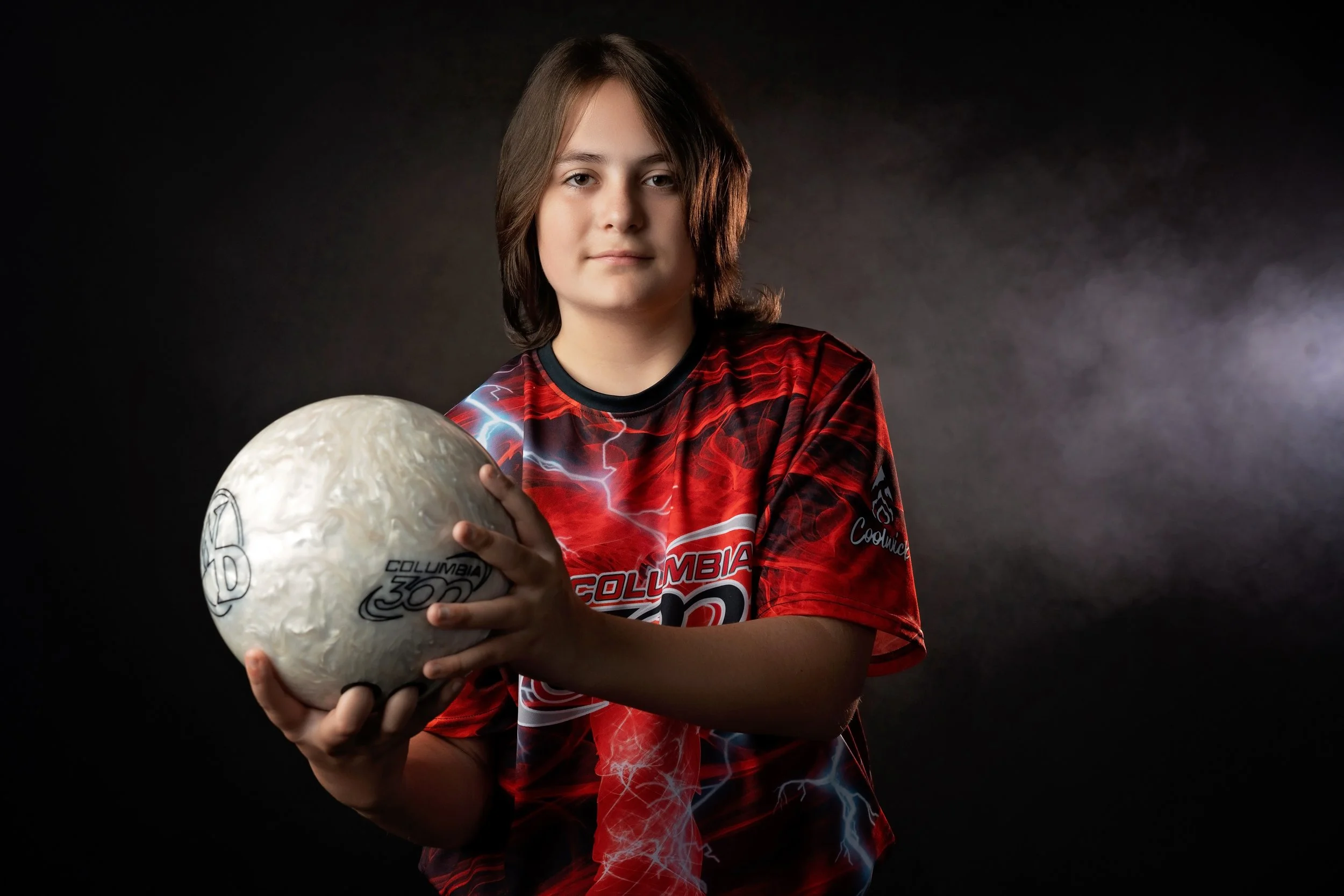 A boy poses with his bowling ball during his sports photography session in Gretna