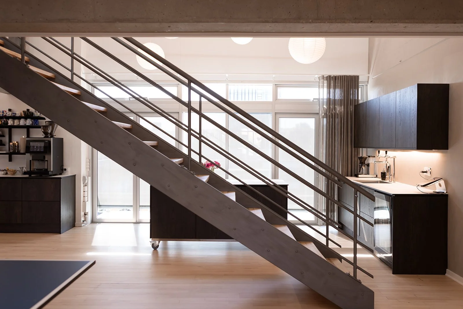 Indendørs køkken med ståltrappe og store vinduer, moderne udseende.