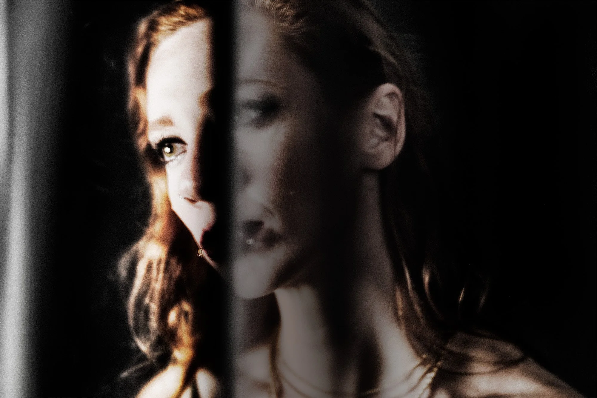 A woman looks at her reflection in a mirror with dim lighting, creating a moody and artistic atmosphere.