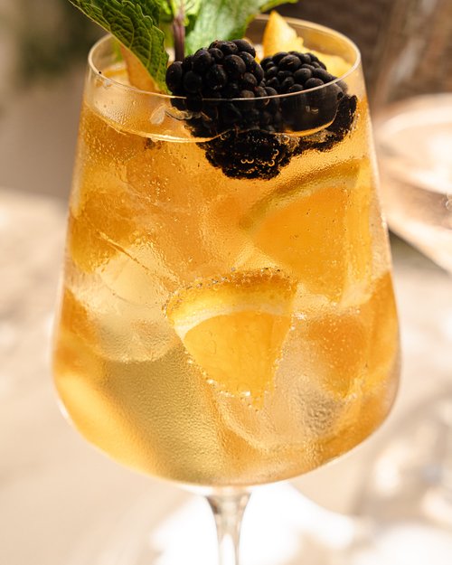 A cocktail topped with blackberries