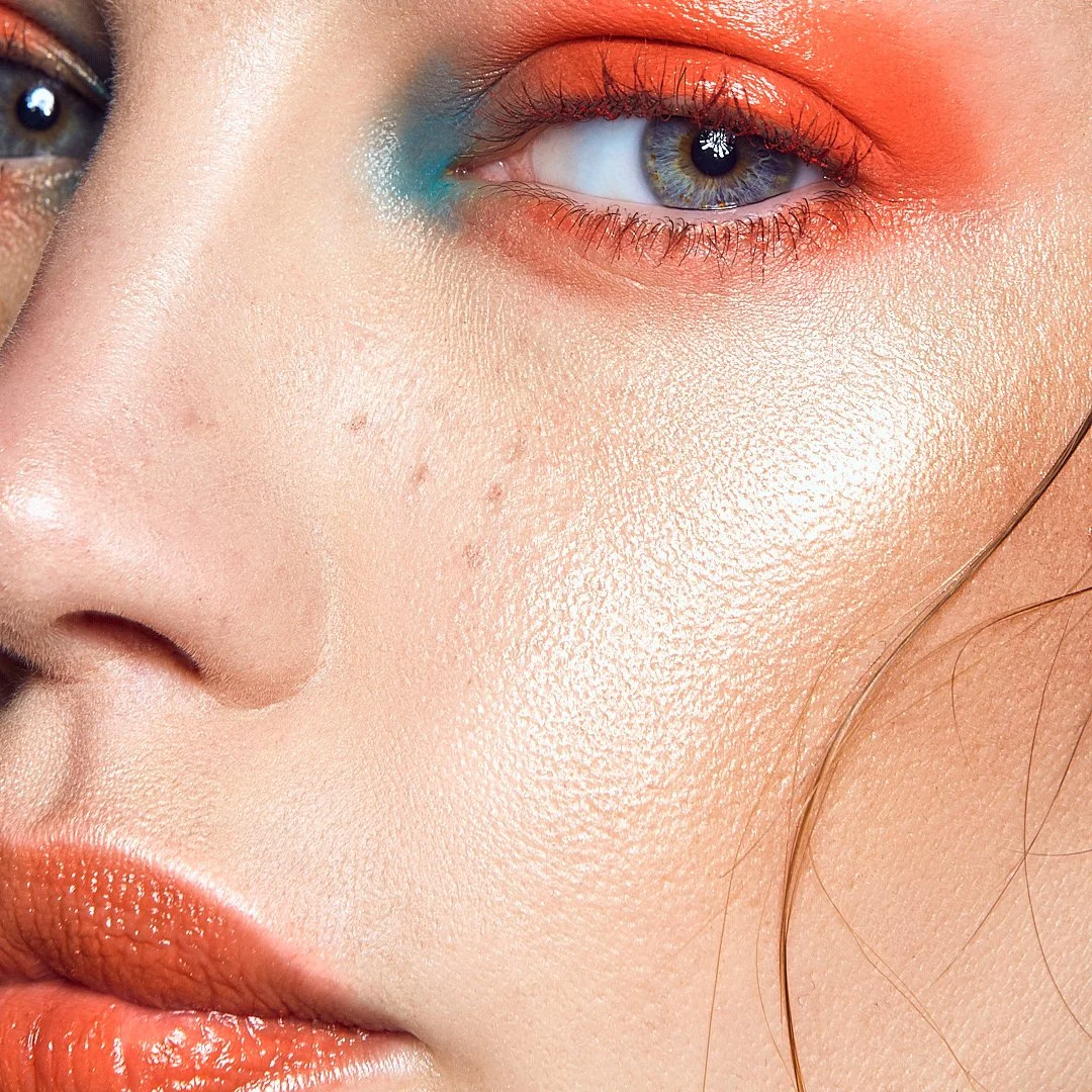 Close-up beauty portrait with colourful eye makeup, smooth skin, and glossy lips, photography by Justin Munitz.