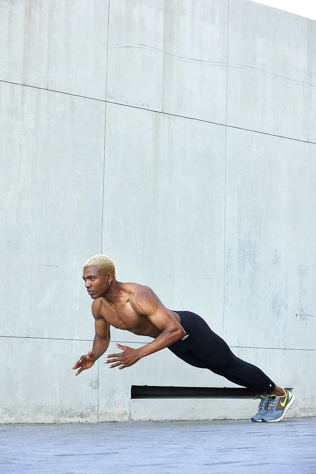 Active lifestyle photography by Justin Munitz — shirtless model performing a push-up against a concrete wall.
