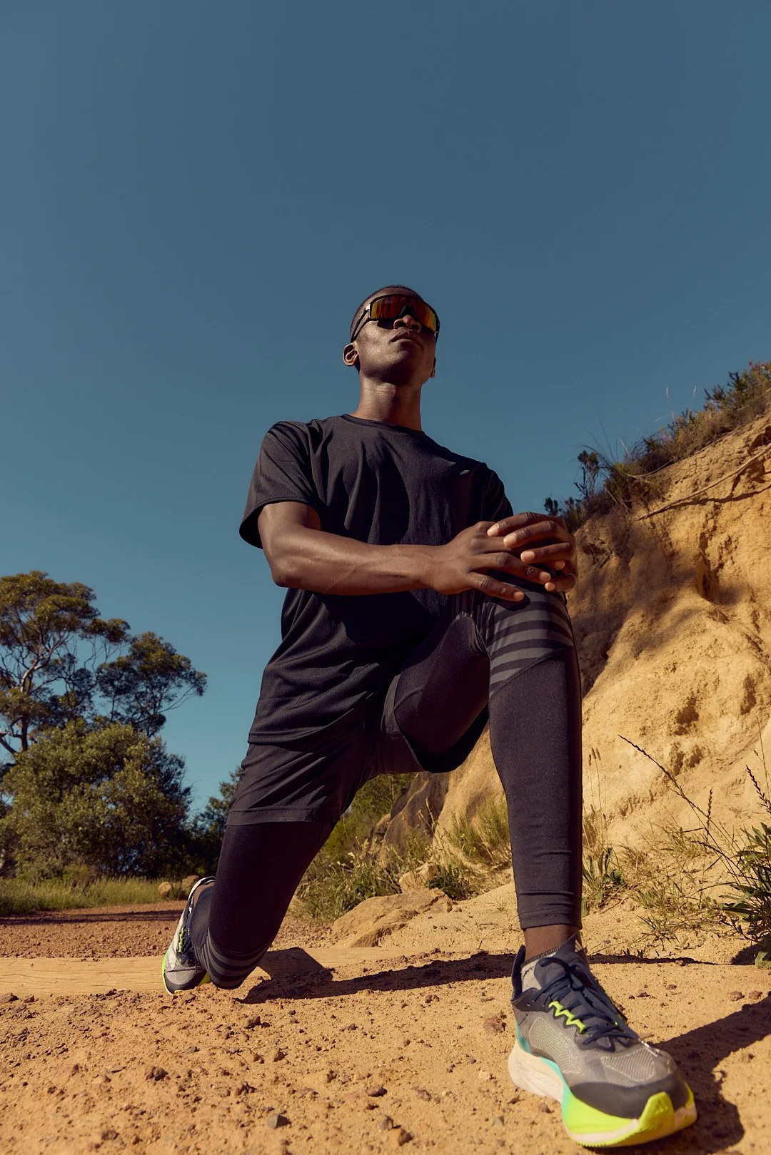 Active lifestyle photography by Justin Munitz — model stretching outdoors on a trail near a sandy hill