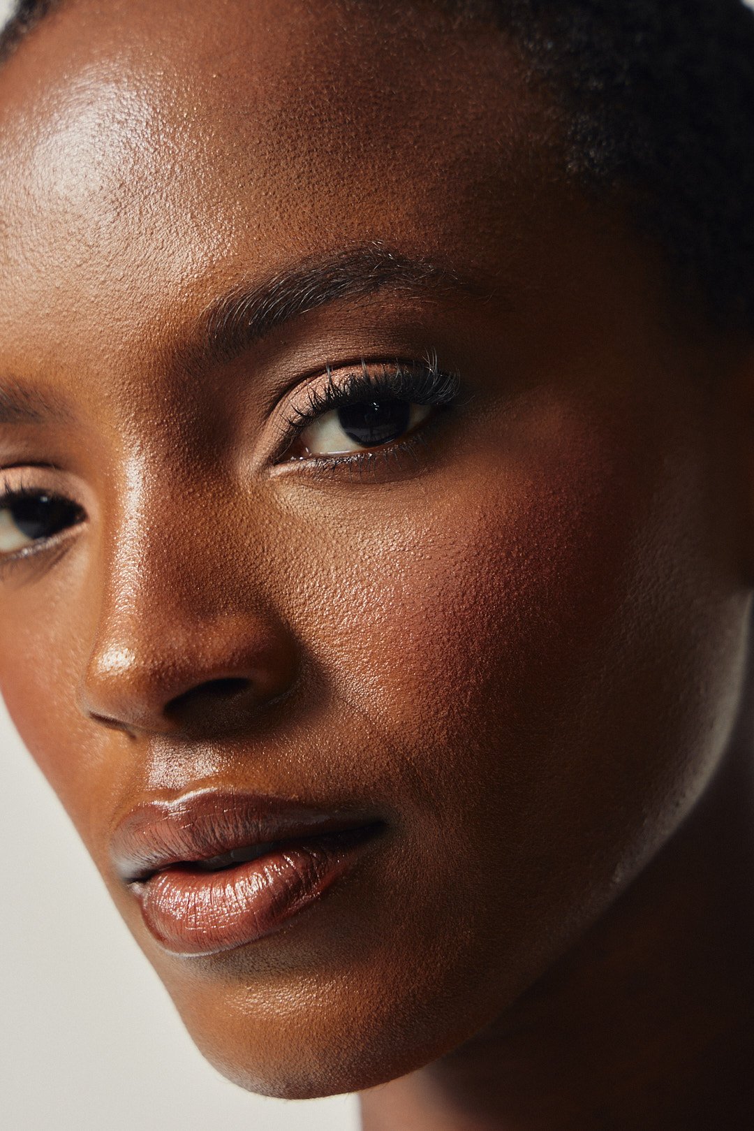 Close-up beauty portrait with glossy full lips and defined lashes, photography by Justin Munitz.