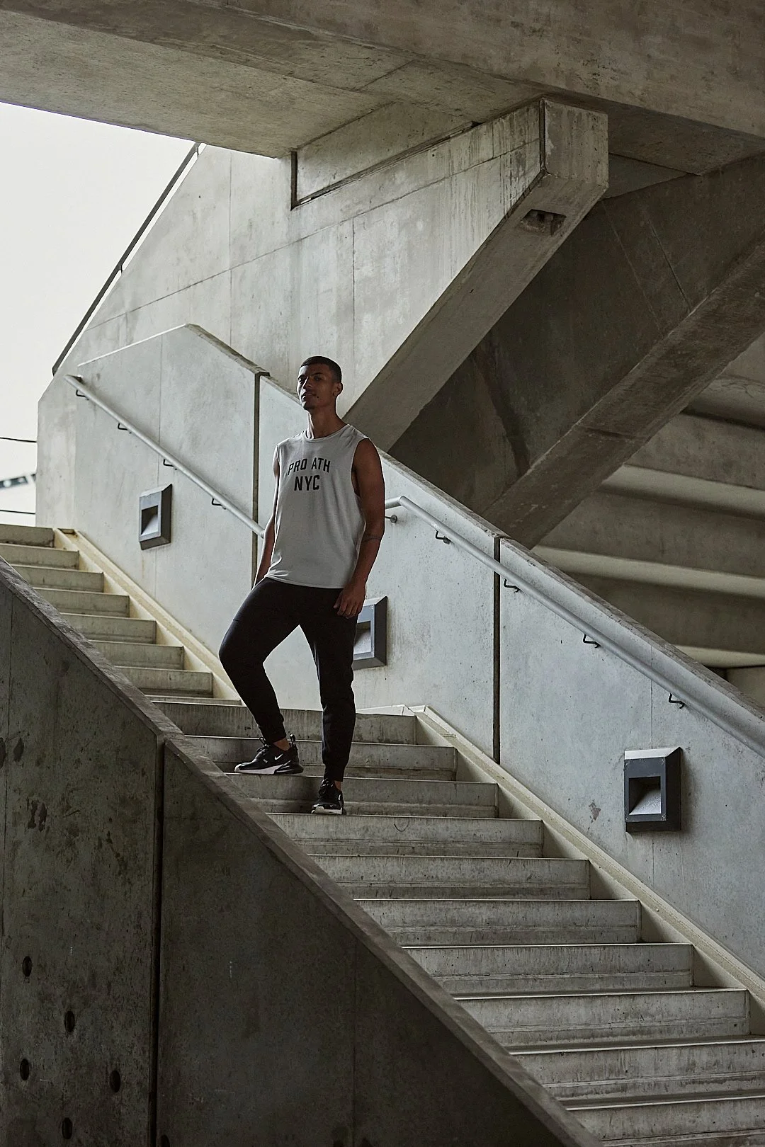 Active lifestyle photography by Justin Munitz - model standing on a concrete staircase in an urban, industrial setting.