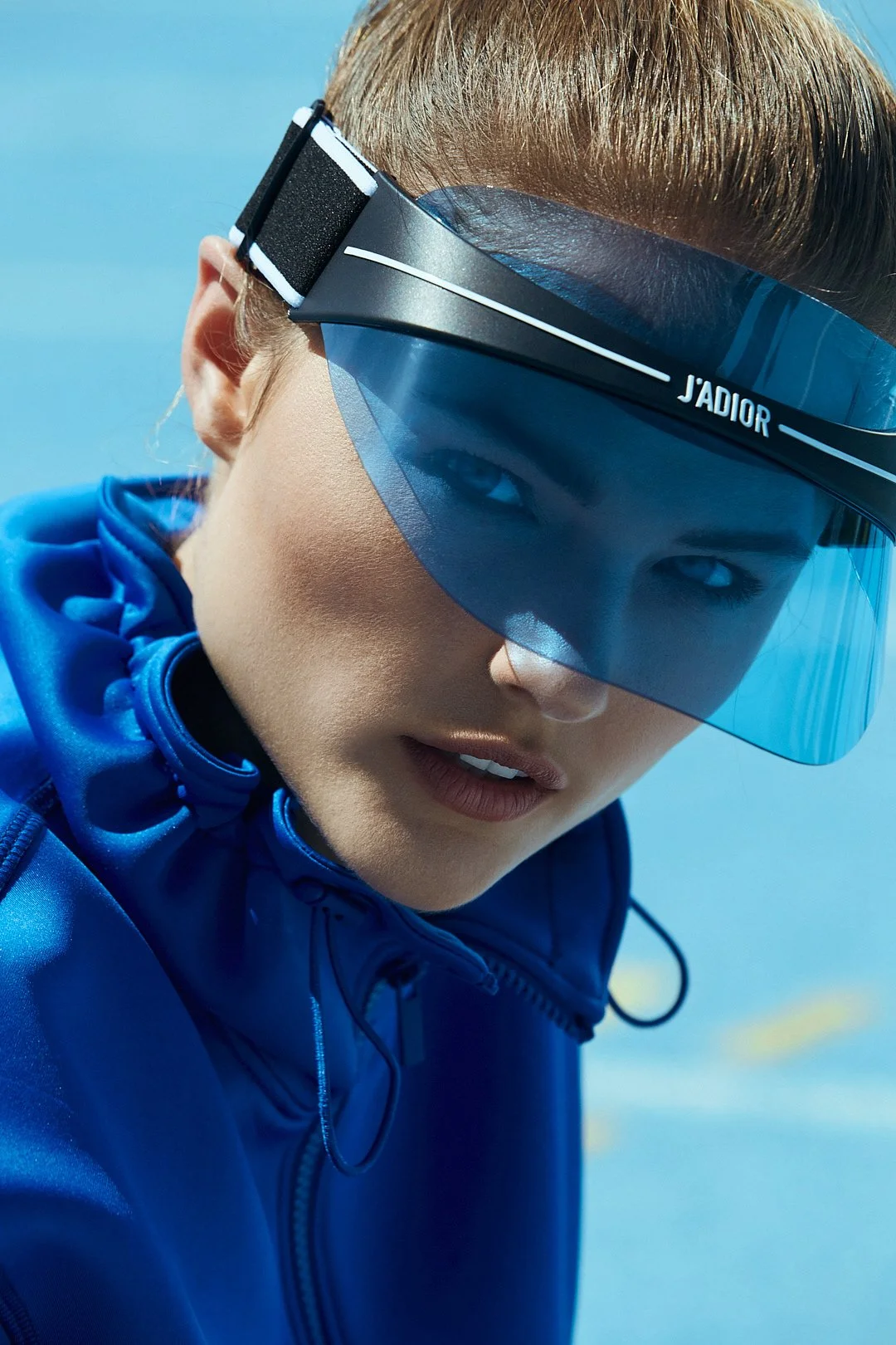 Active lifestyle photography by Justin Munitz - close-up of a model wearing a blue sports jacket and tinted visor, outdoors.