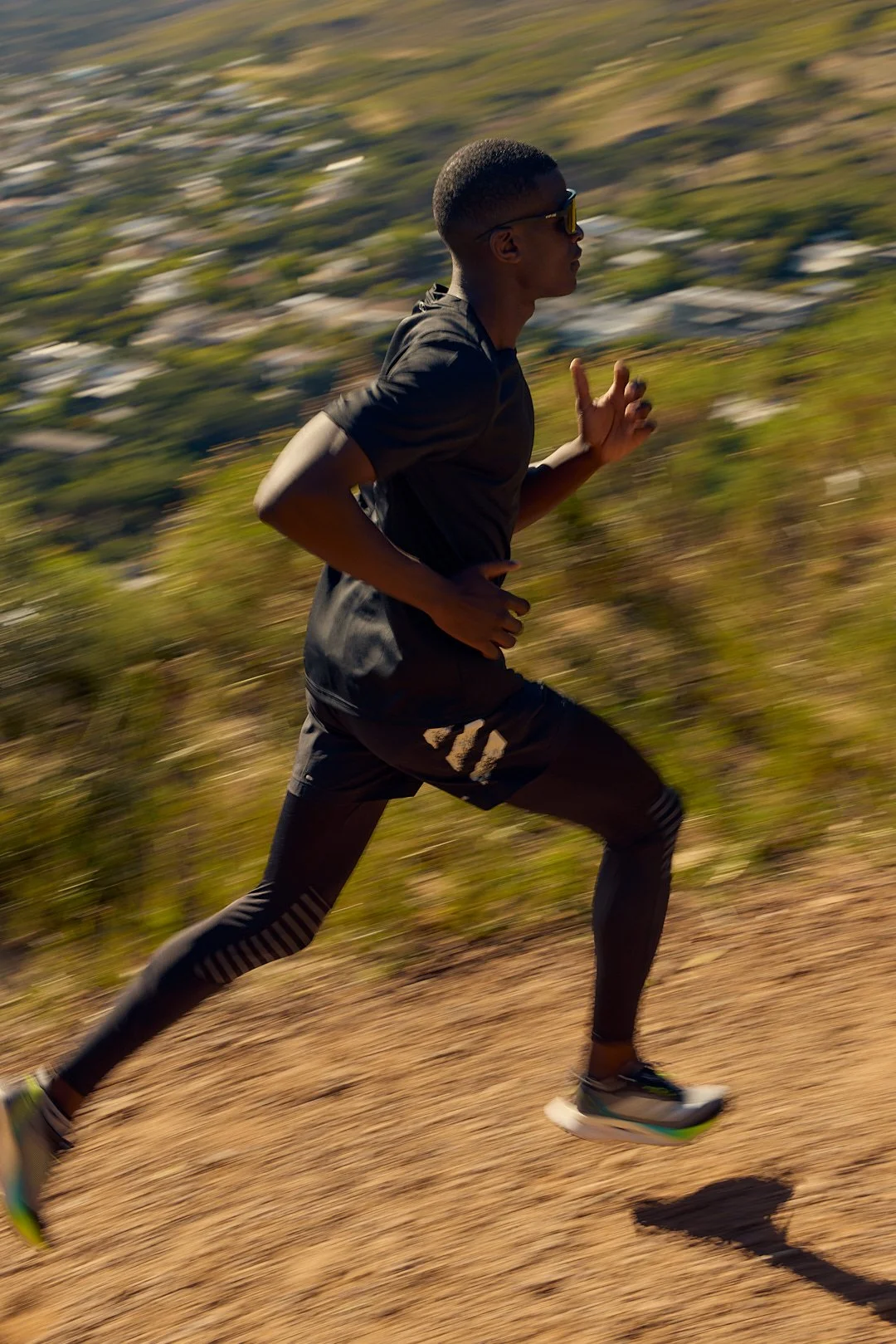 Active lifestyle photography by Justin Munitz - model running on a dirt trail, with hills in the background