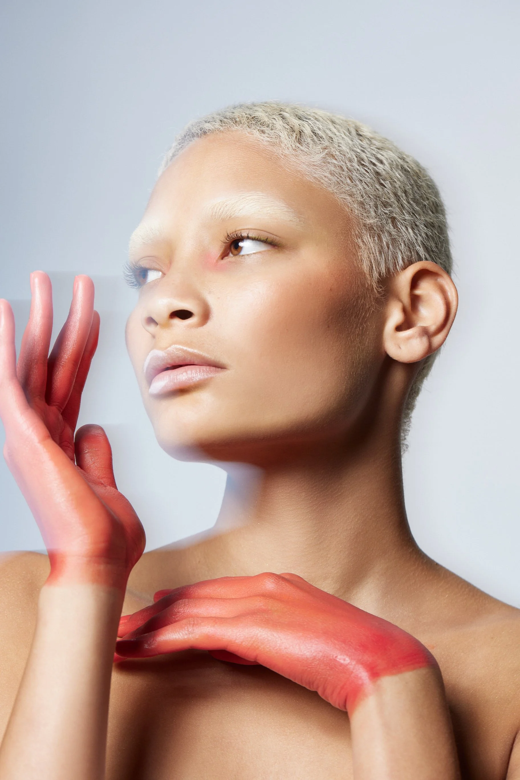 Close-up beauty portrait with minimal makeup and a reddish-orange tinted shirt draped over the shoulders, photography by Justin Munitz.