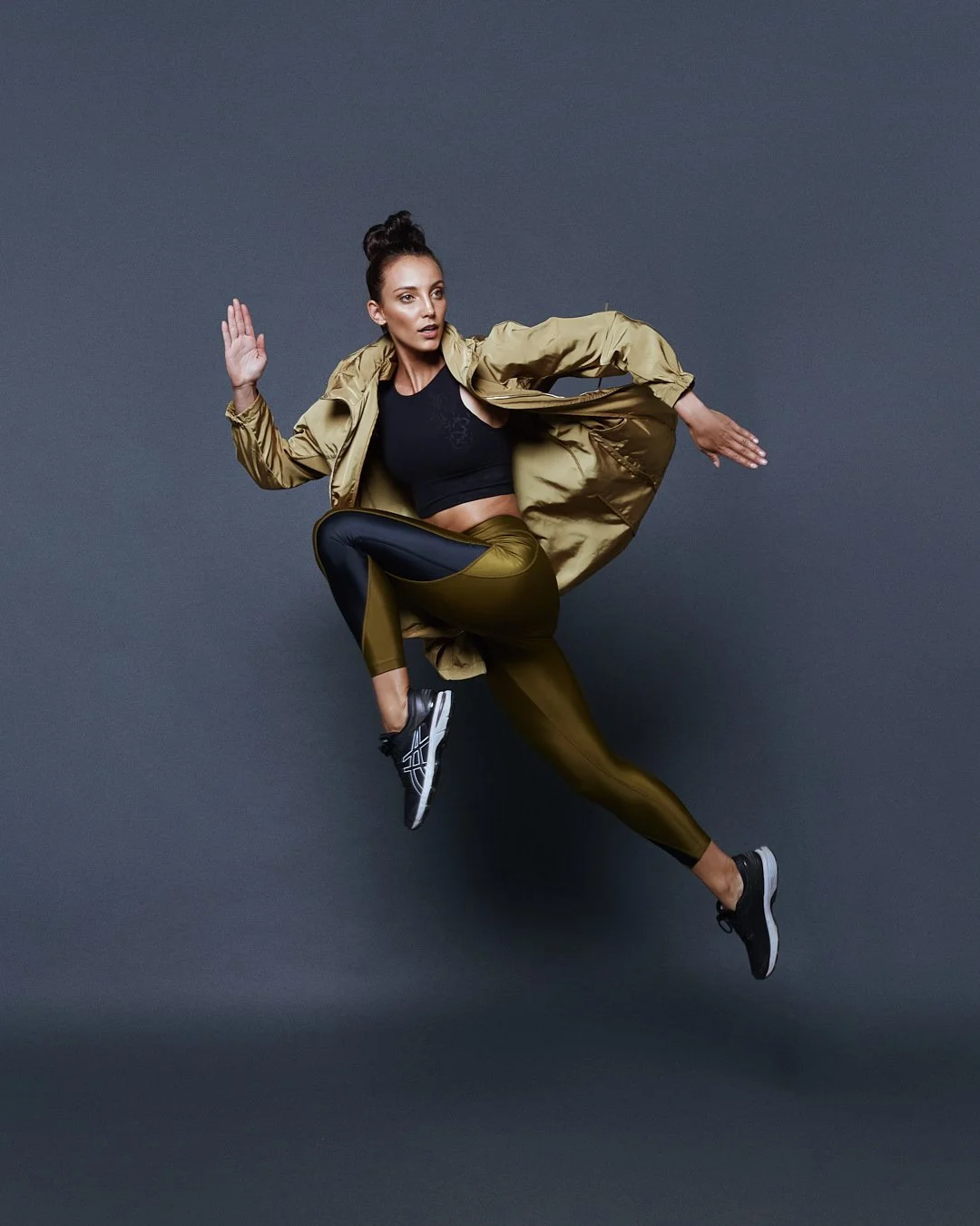 Active lifestyle photography by Justin Munitz. A model in athletic clothing jumping mid-air against a gray background