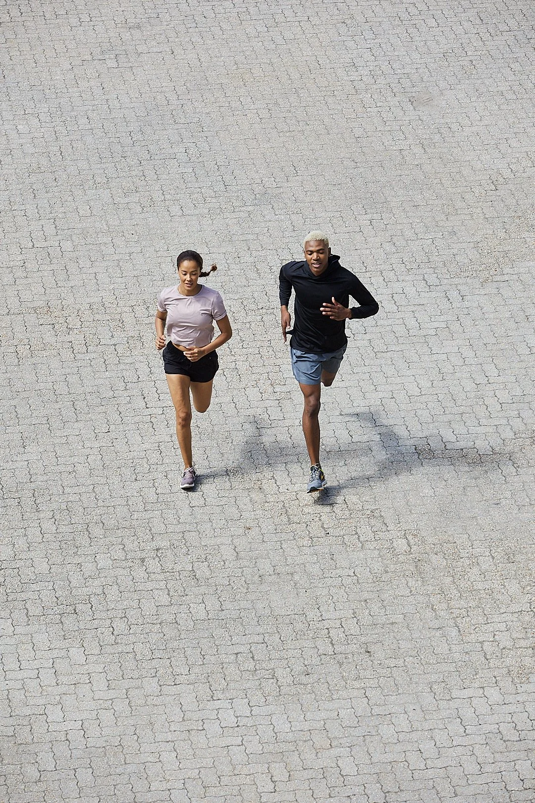 Active lifestyle photography by Justin Munitz - two models running on a paved surface, viewed from above.