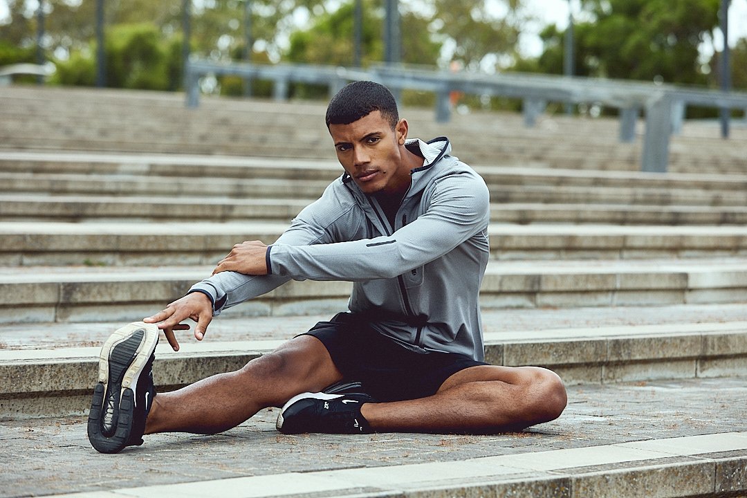 Active lifestyle photography by Justin Munitz - model stretching outdoors on concrete stairs in a park.