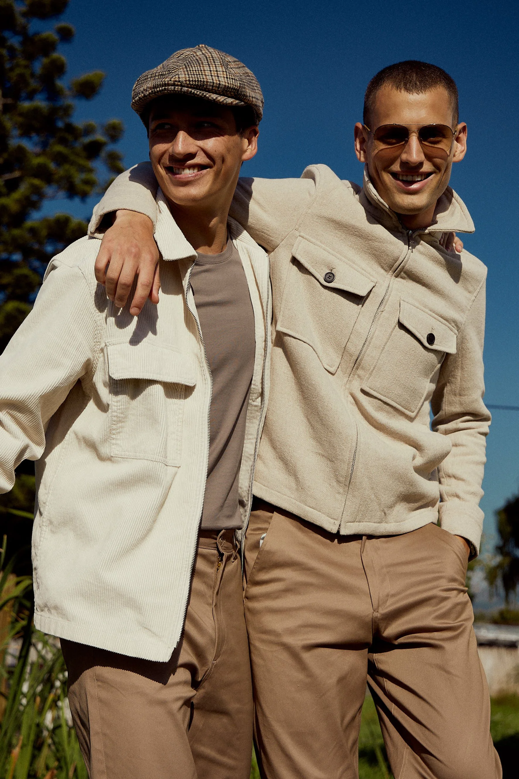 Fashion photography by Justin Munitz - two models walking outdoors in casual jackets, arms around each other's shoulders