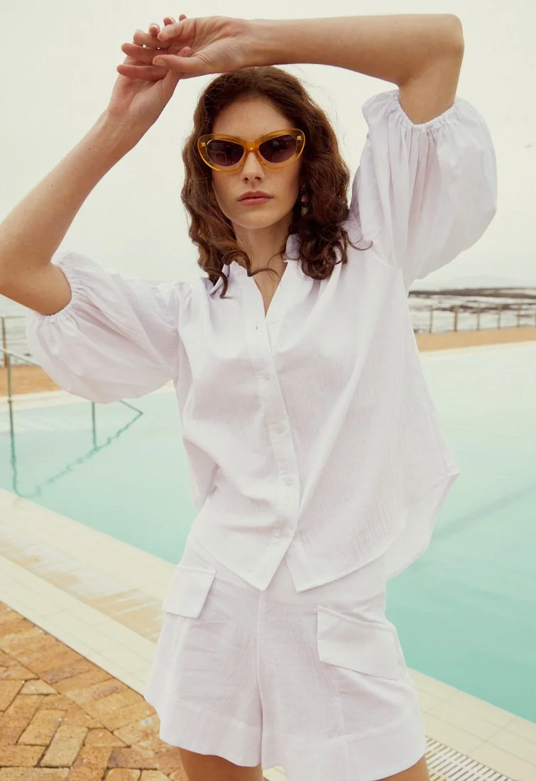 Fashion photography by Justin Munitz - model in a white outfit posing beside a swimming pool