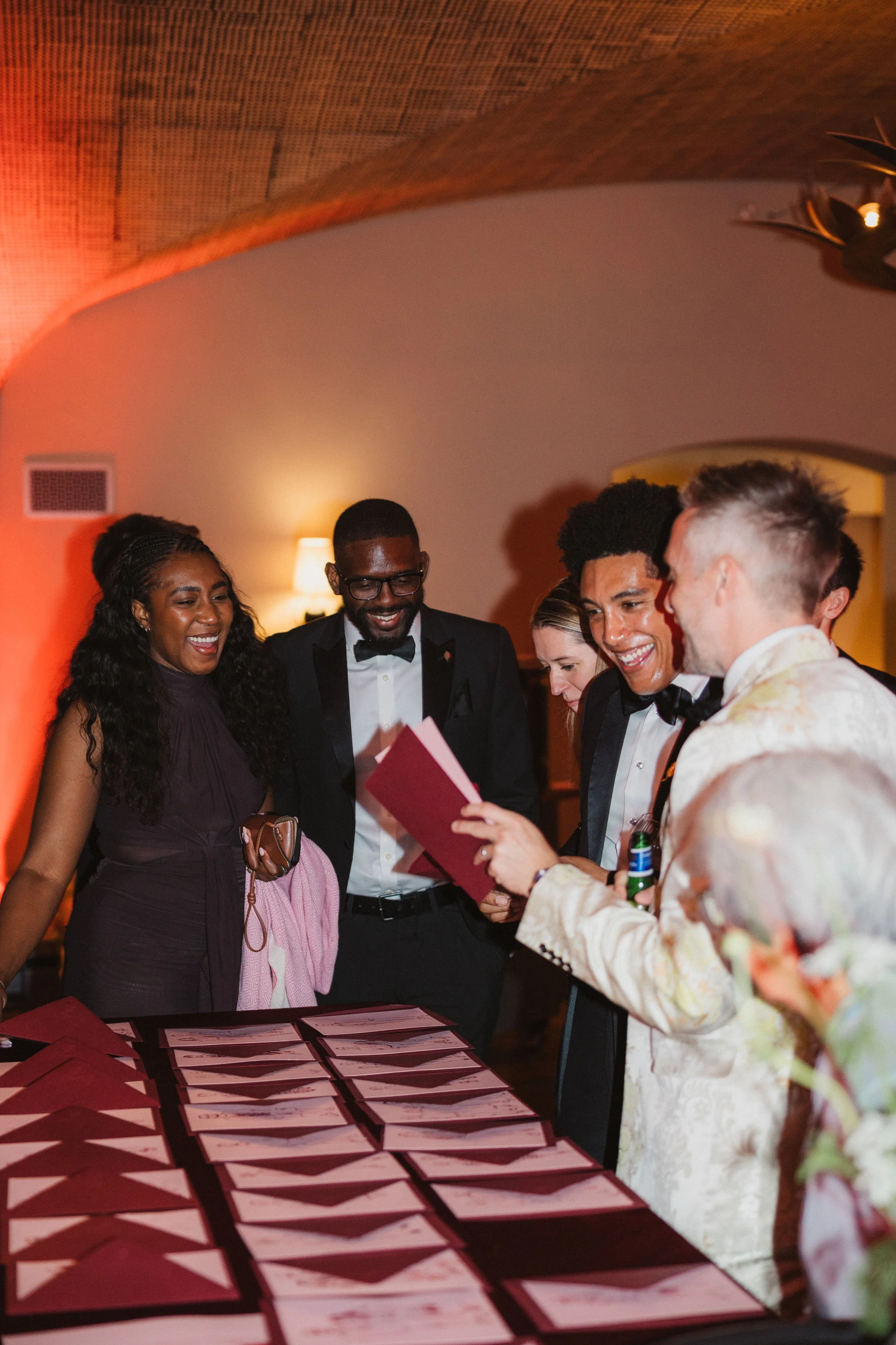 Wedding guests laughing while finding their illustrated portrait place cards at a reception escort card table