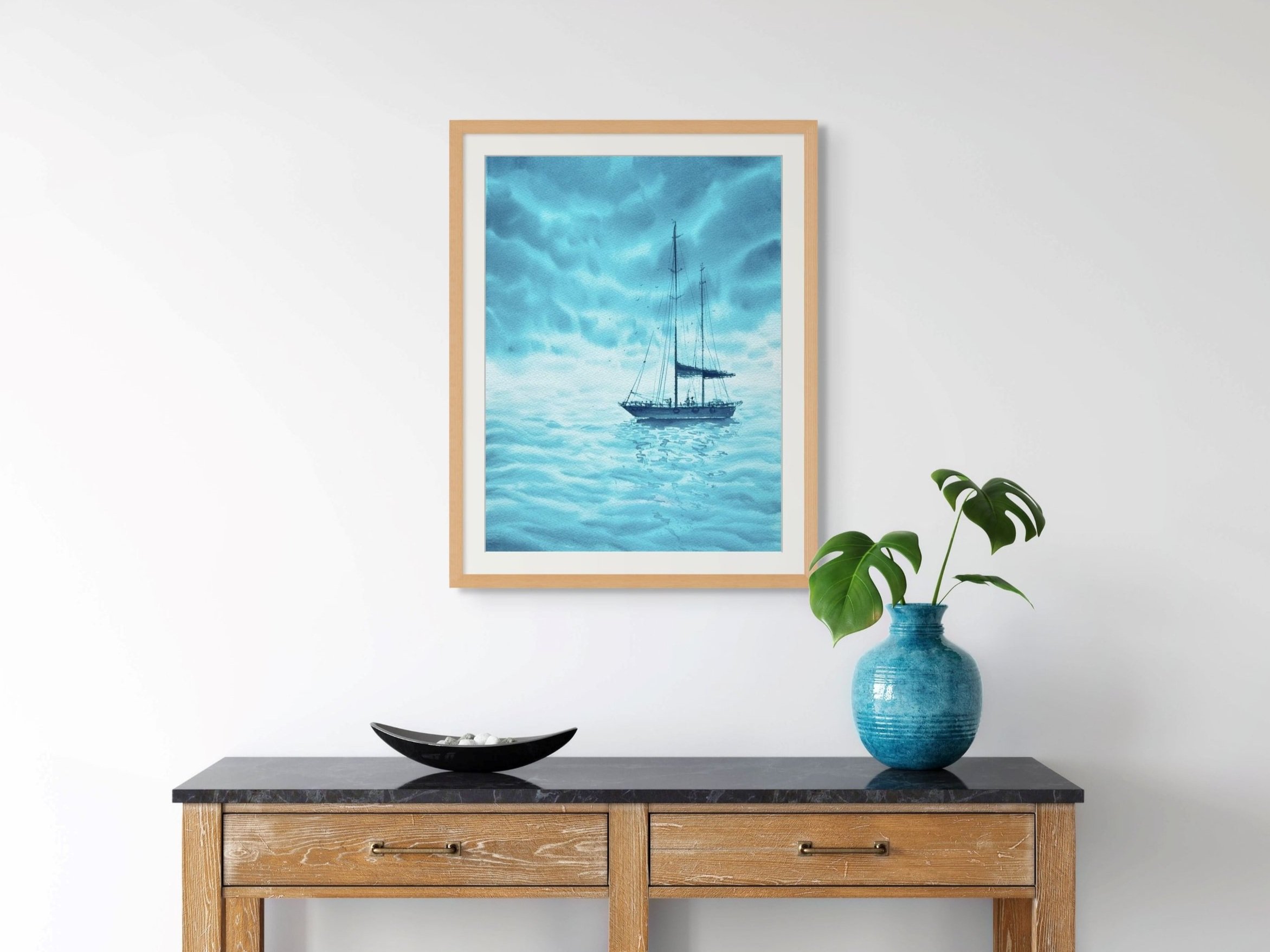 Turquoise Dreams is an Original Watercolor Painting of a Sailing Boat on Black Sea during a Regatta. In this set up the paintings is framed with wooden frame on a dispaly shelf with a blue vase.
