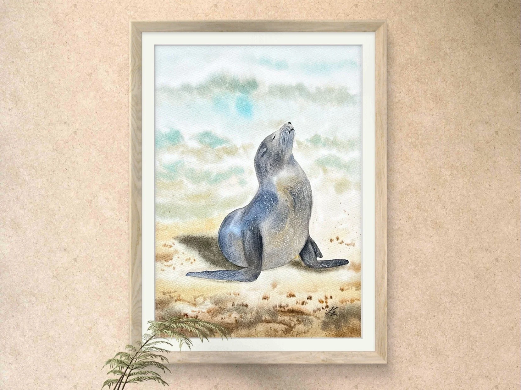 This original watercolor features a gentle Sunbathing Seal on the beach, painted in impressionistic style. The painting is staged for photographs in a livingroom setup.
