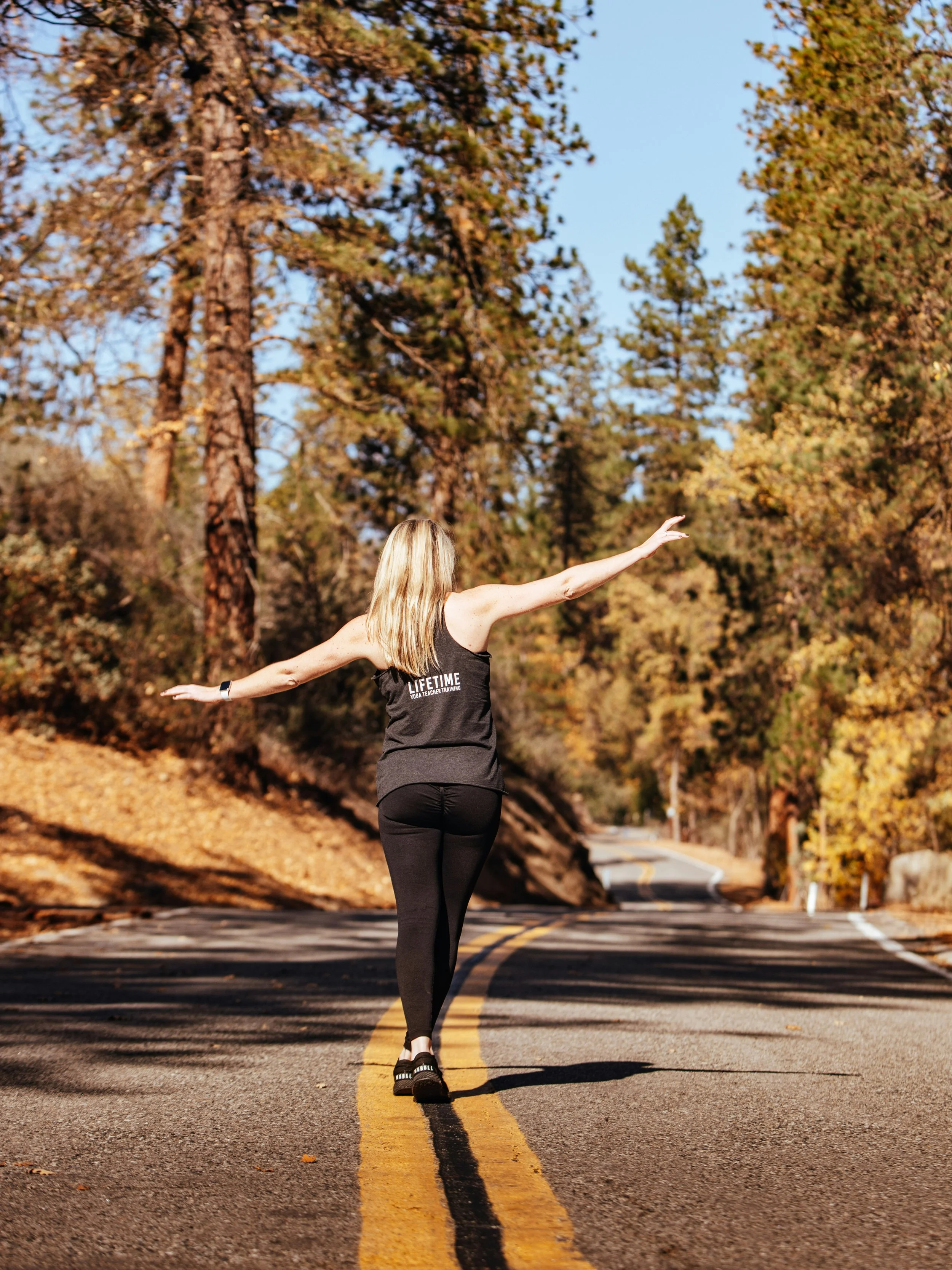 sporty woman walking along wavy yellow lines in middle of the road