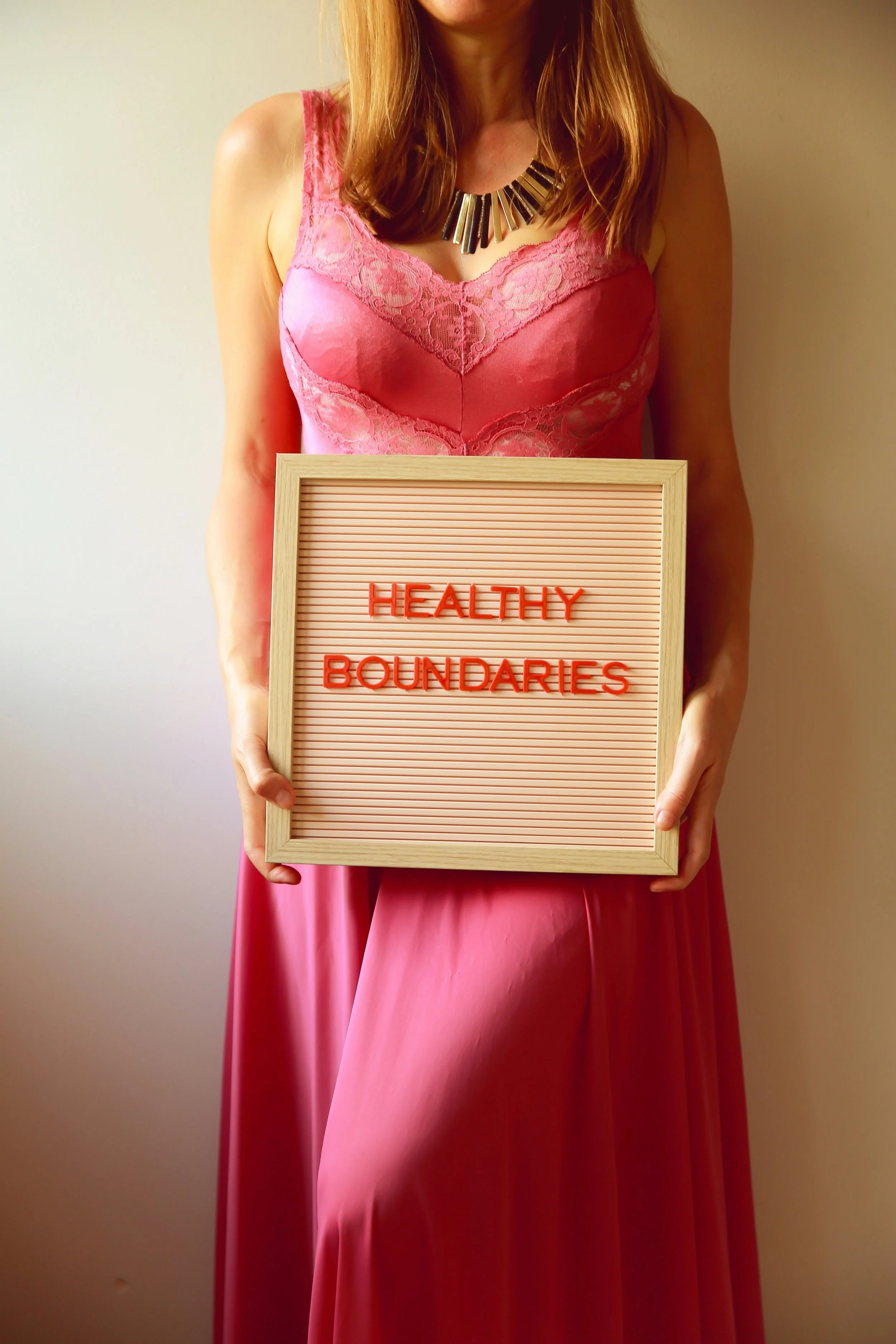 blonde women in pink dress holding a sign saying 'Healthy Boundaries'