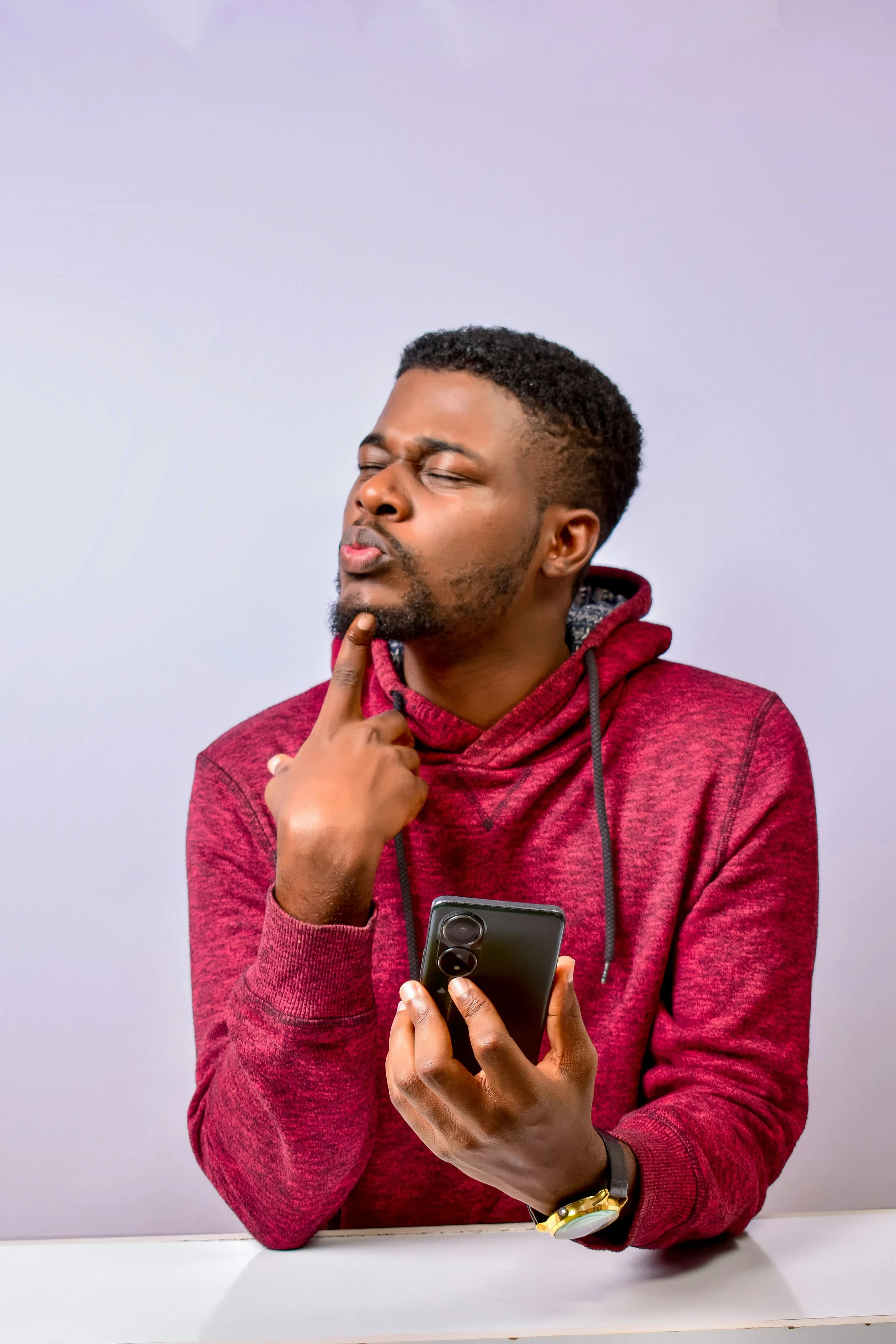 man in cherry red hoodie looking confusedly at phone