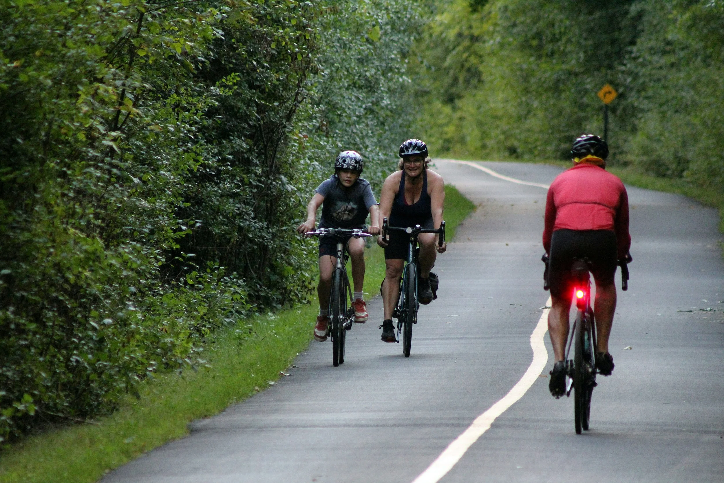 mother and son cycling past midlife man on leafy cycle path