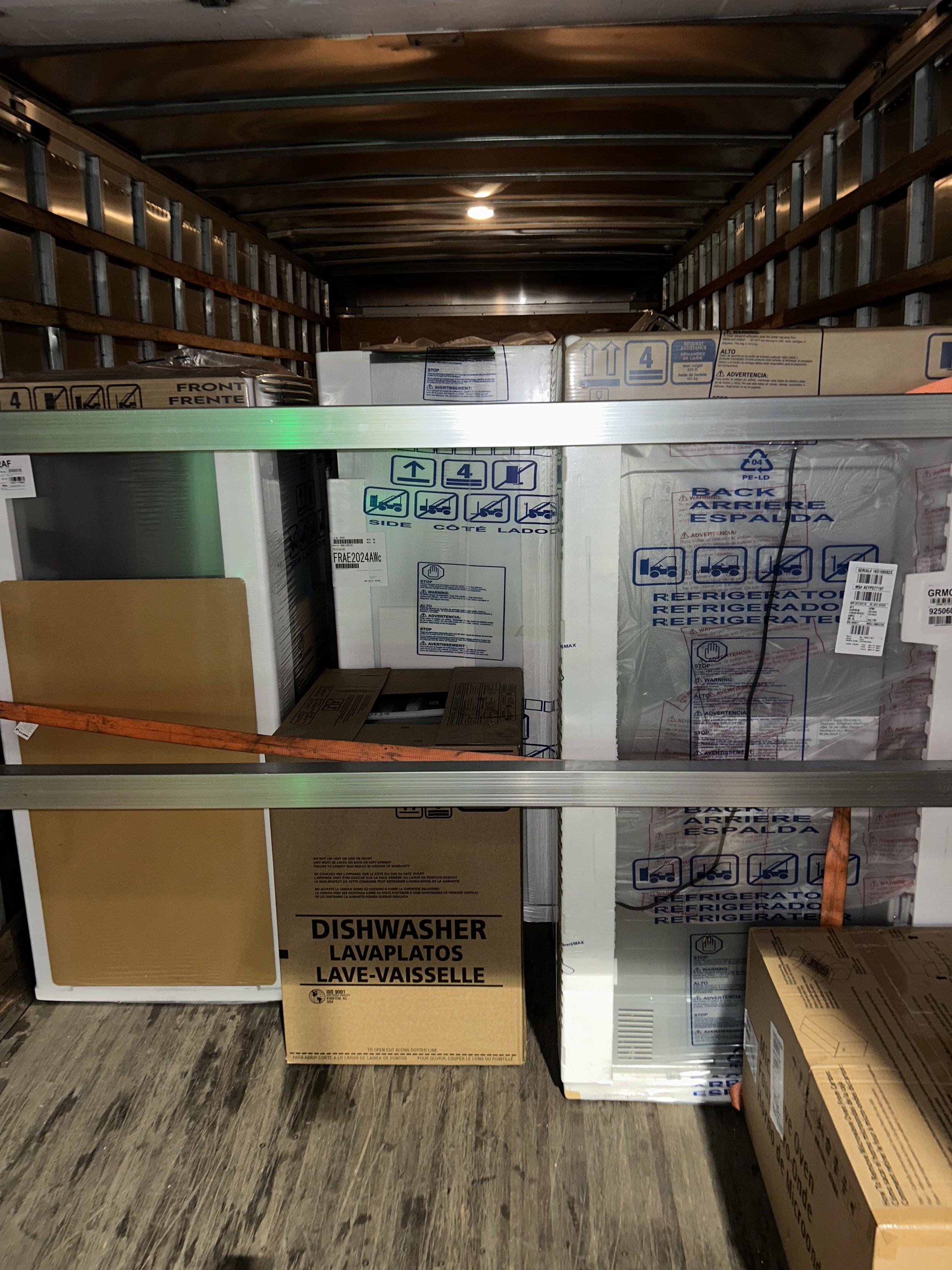 A moving truck shelf with boxed appliances, including a dishwasher and refrigerator.
