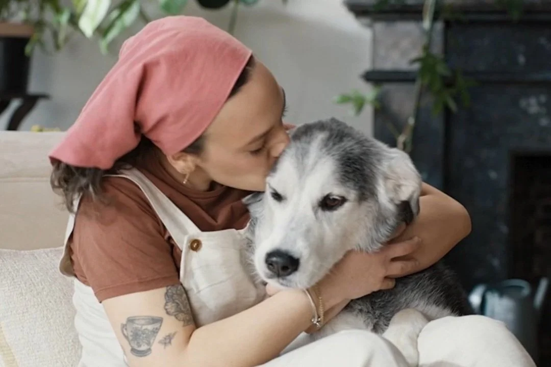 Woman kissing her dog on the head