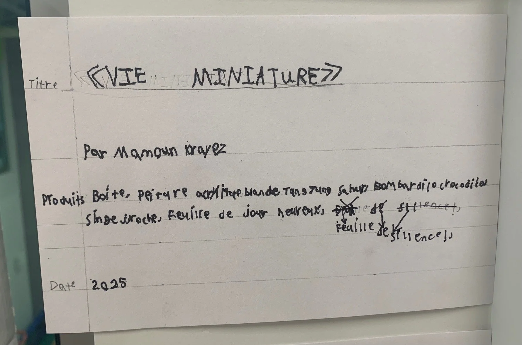 Page écrite à la main avec un titre 'VIE MINIATURE' écrit en grand, un nom d'auteur 'Par Mamoun Krayes', une description de produits artisanaux comme une boîte, une peinture, une poupée blanche, un singe en porcelaine, une feuille de jour heureux, et