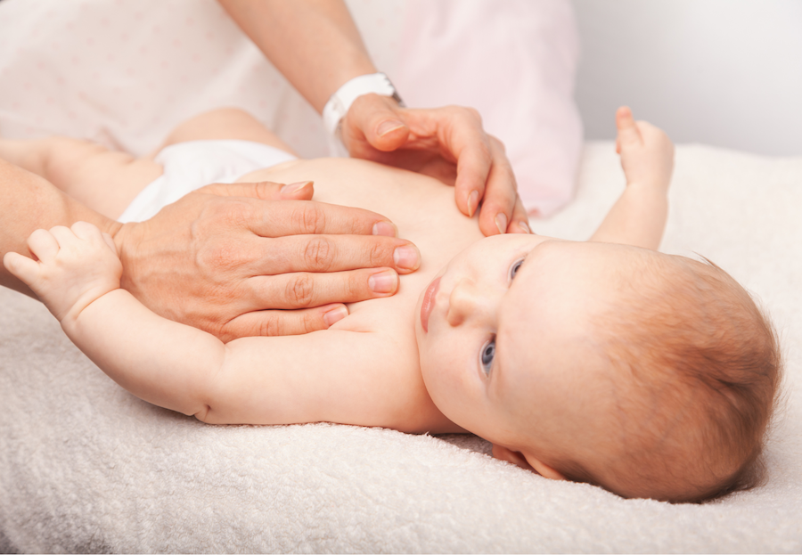 Ein Baby bekommt osteopathisch den Bauch behandelt.