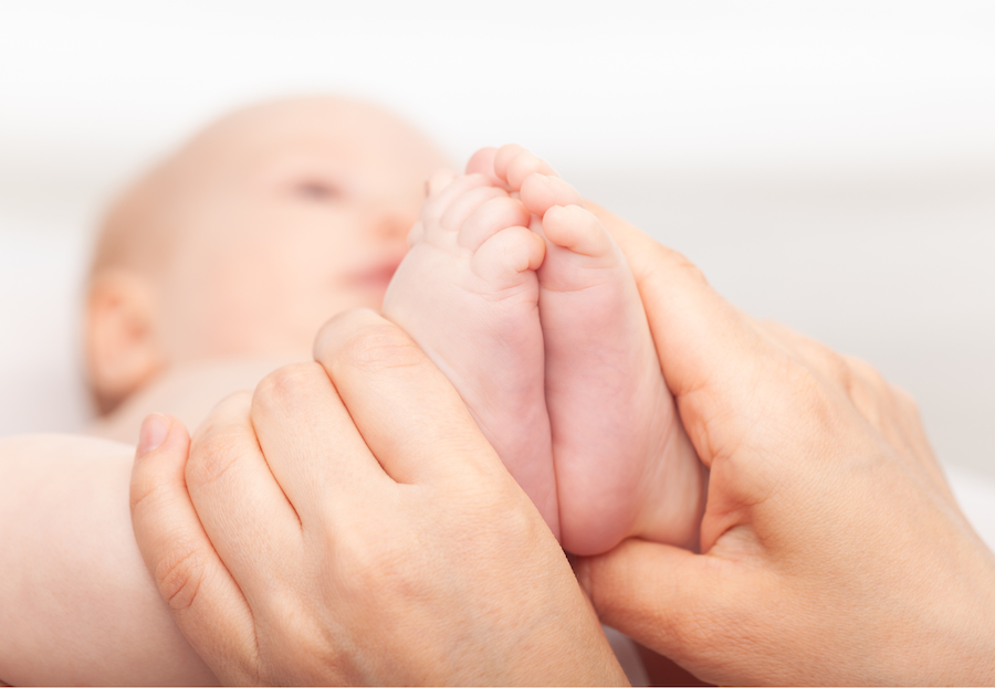 Ein Baby bekommt osteopathisch die Füße behandelt.