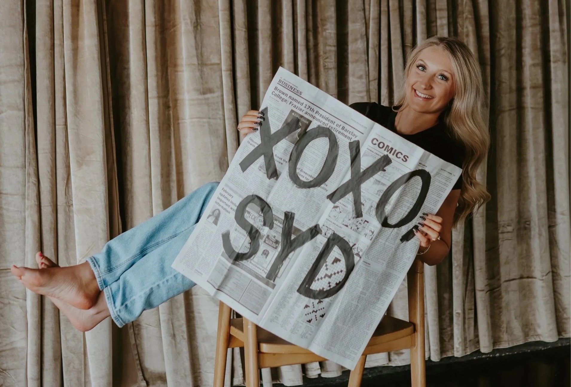 Sydney, designer behind StudioSyd, holding a StudioSyd newspaper during a branding photoshoot.