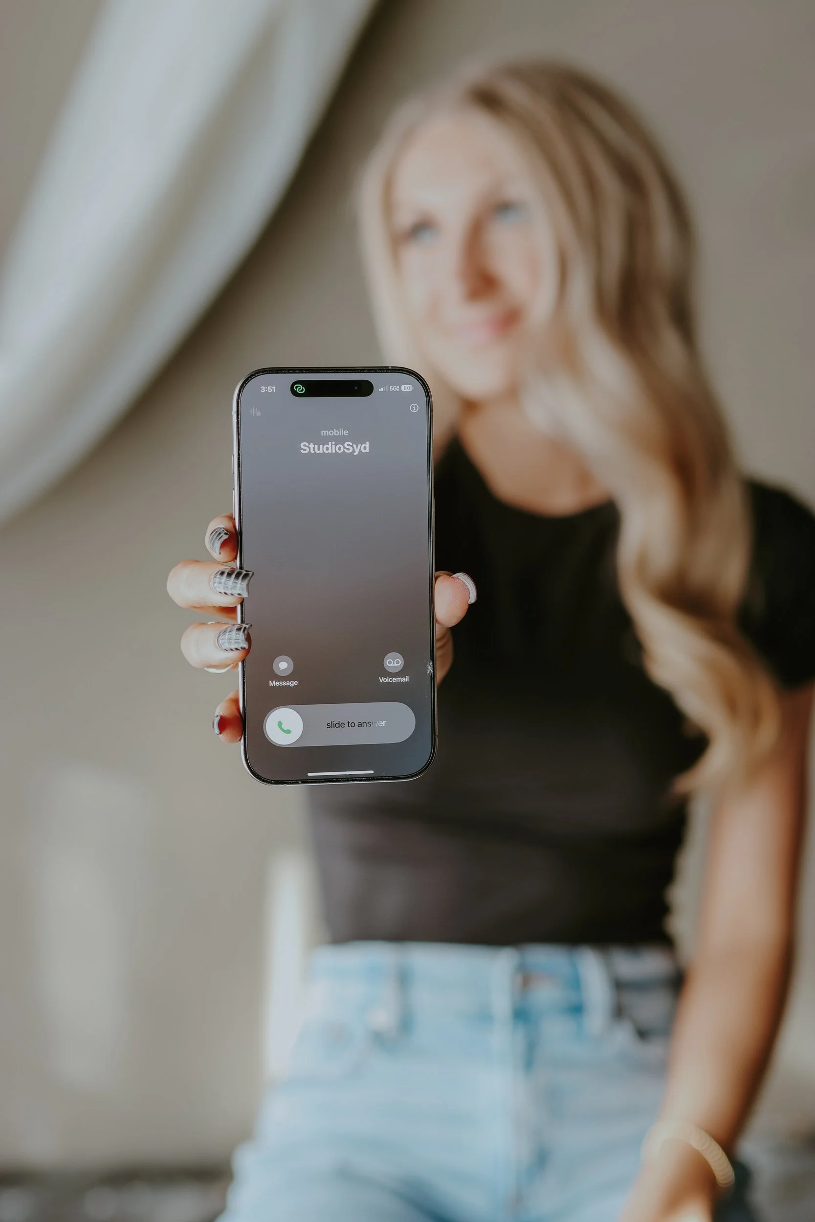 Sydney holding a phone showing an incoming call from StudioSyd.