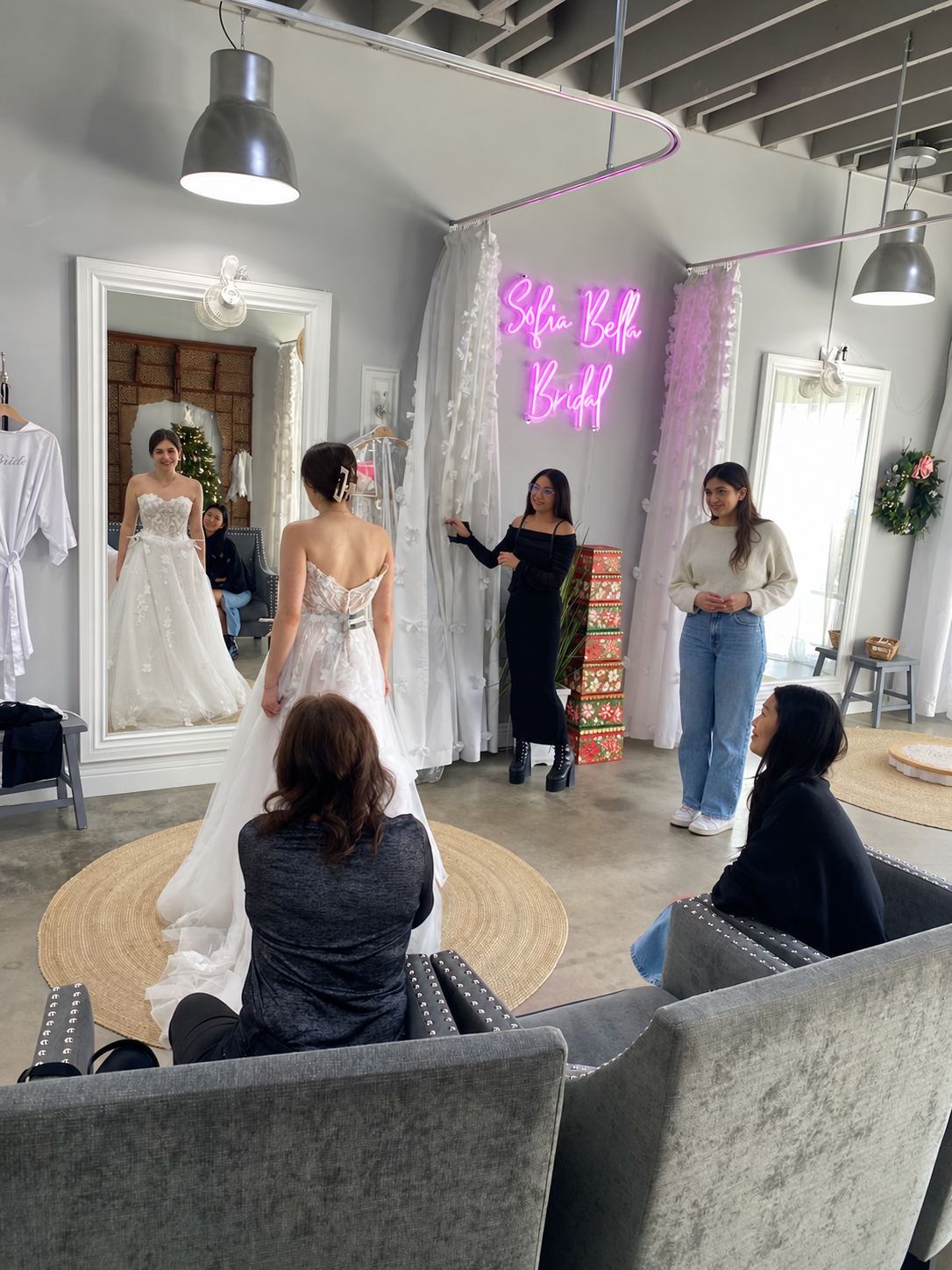 Bride trying on a lace wedding gown with family and friends during a private appointment at Sofia Bella Bridal