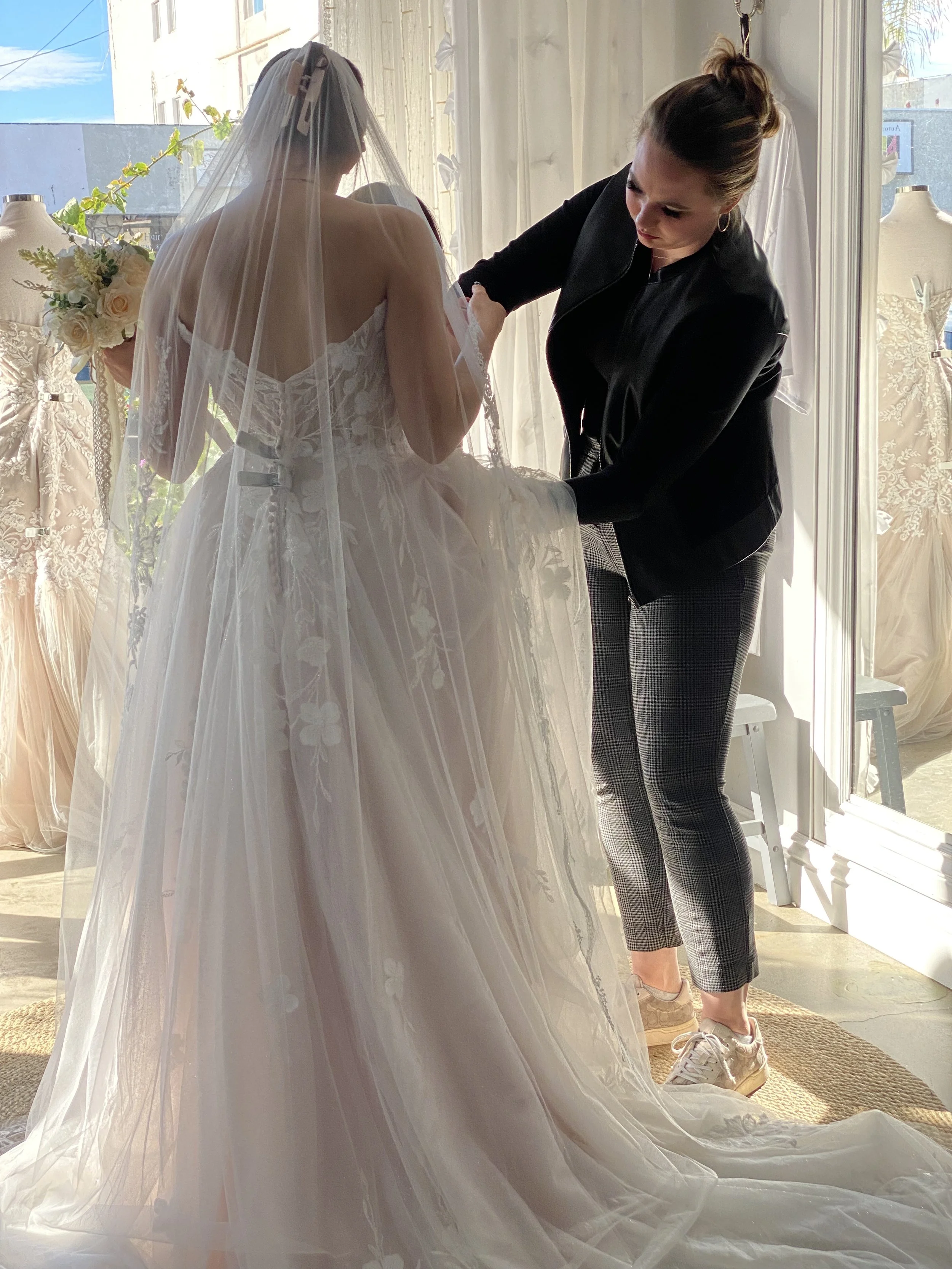 Bridal stylist adjusting a bride’s wedding gown during a personalized appointment at Sofia Bella Bridal.