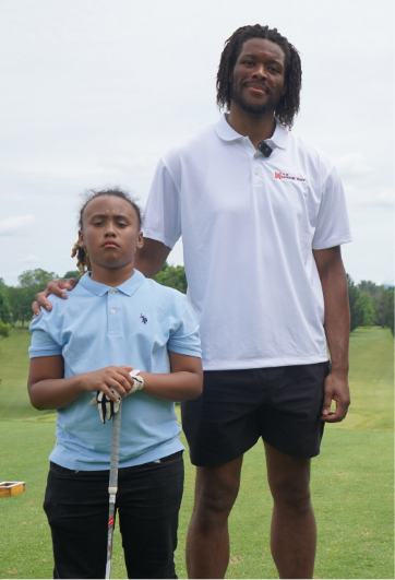 mylyjael poteat taking a picture with a kid at a charity golf event.