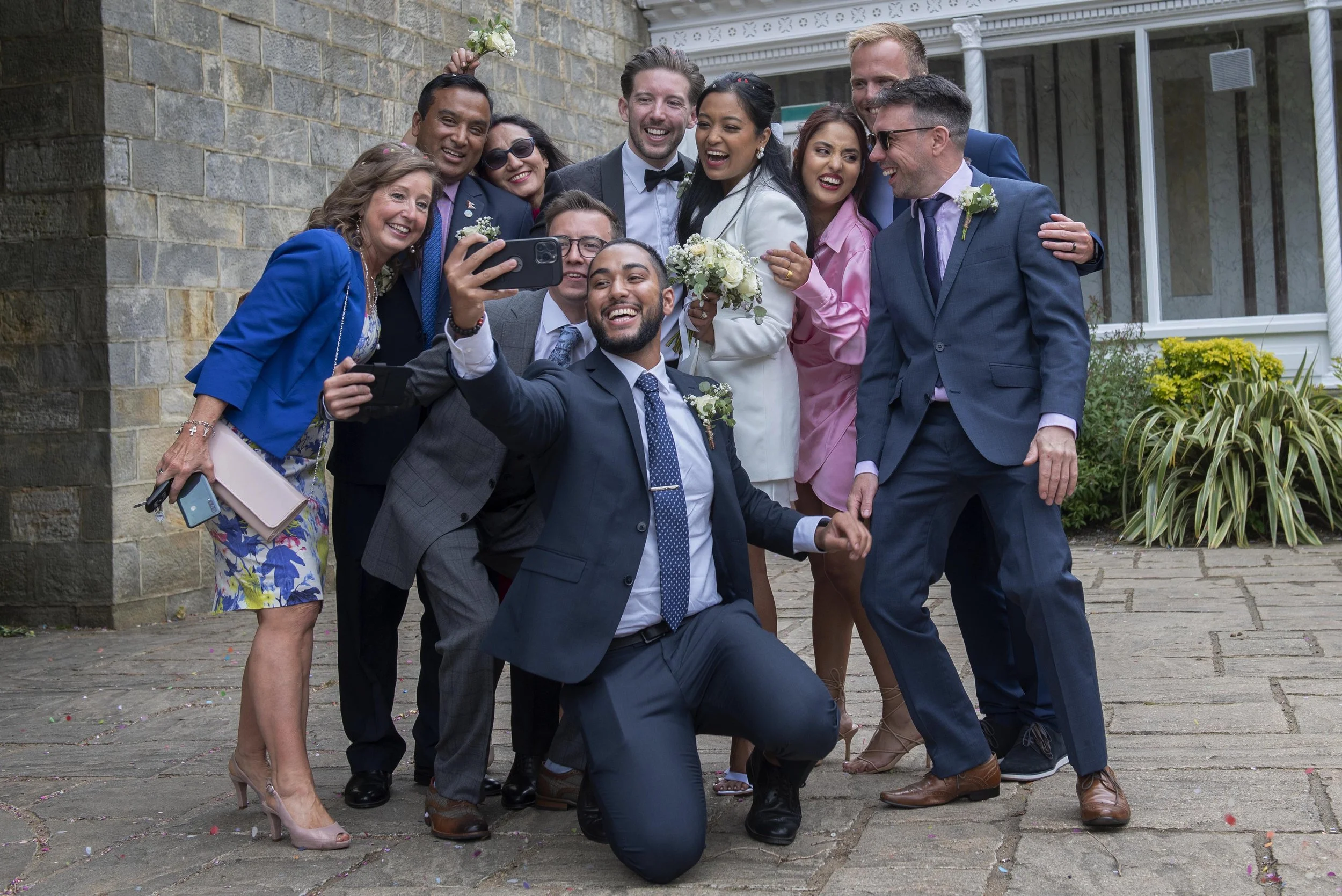 weddings guest gathering around to take a selfie with phone with the bride and groom in Harrogate
