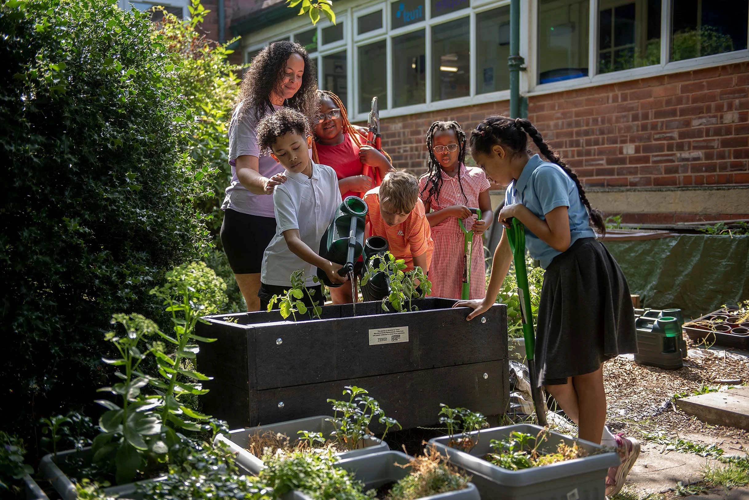 school children and teacher watering plants in the school garden in Sheffield