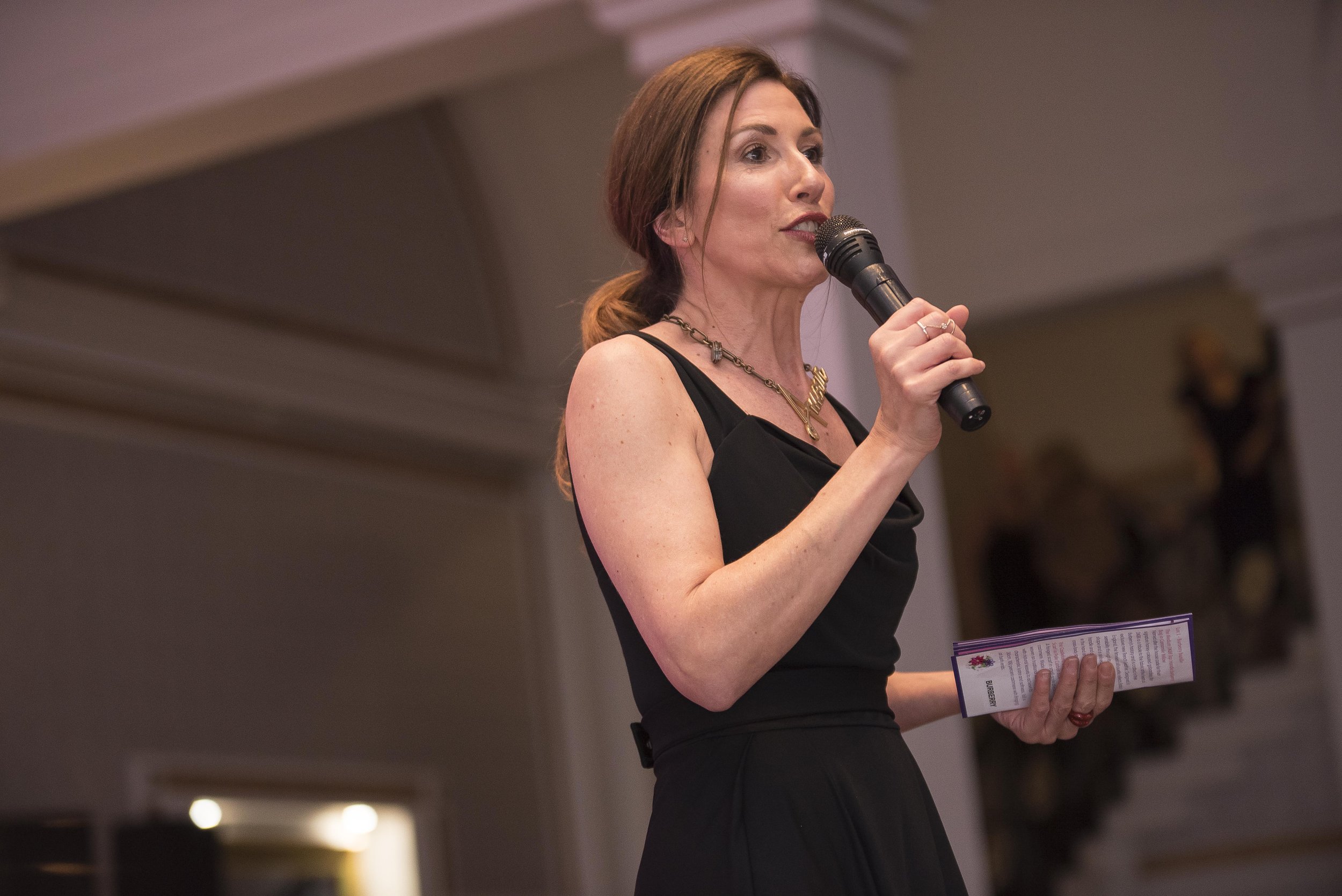 chaity ball woman presenter wearing a black dress and holding a microphone. Breast Cancer Haven Leeds