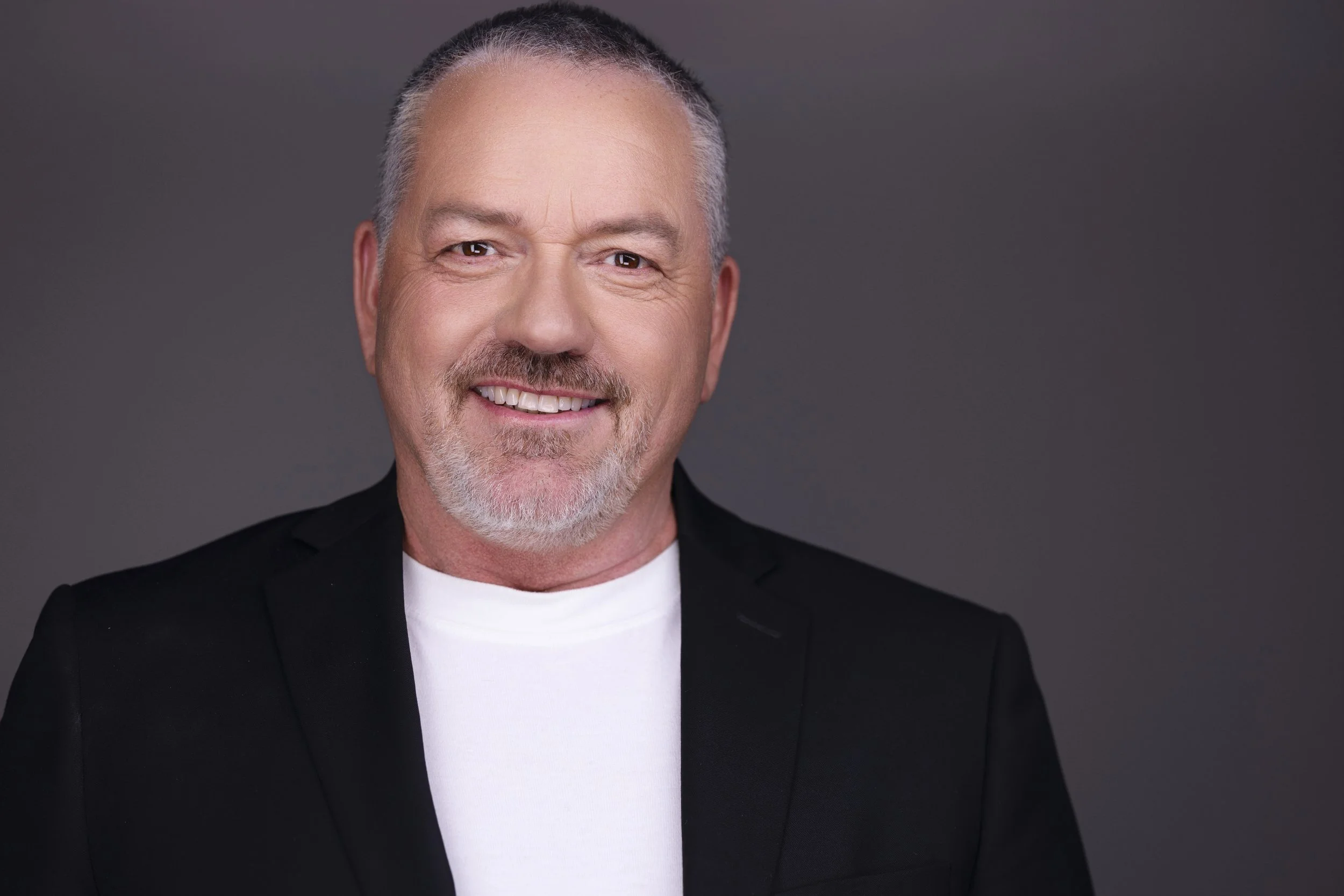 Smiling person in a suit standing indoors.
